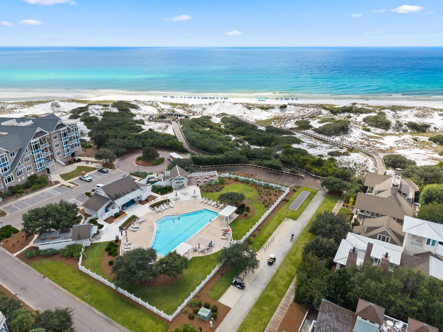 A coastal resort community with direct beach access, a sparkling pool, and pathways leading through natural dunes to pristine turquoise waters.