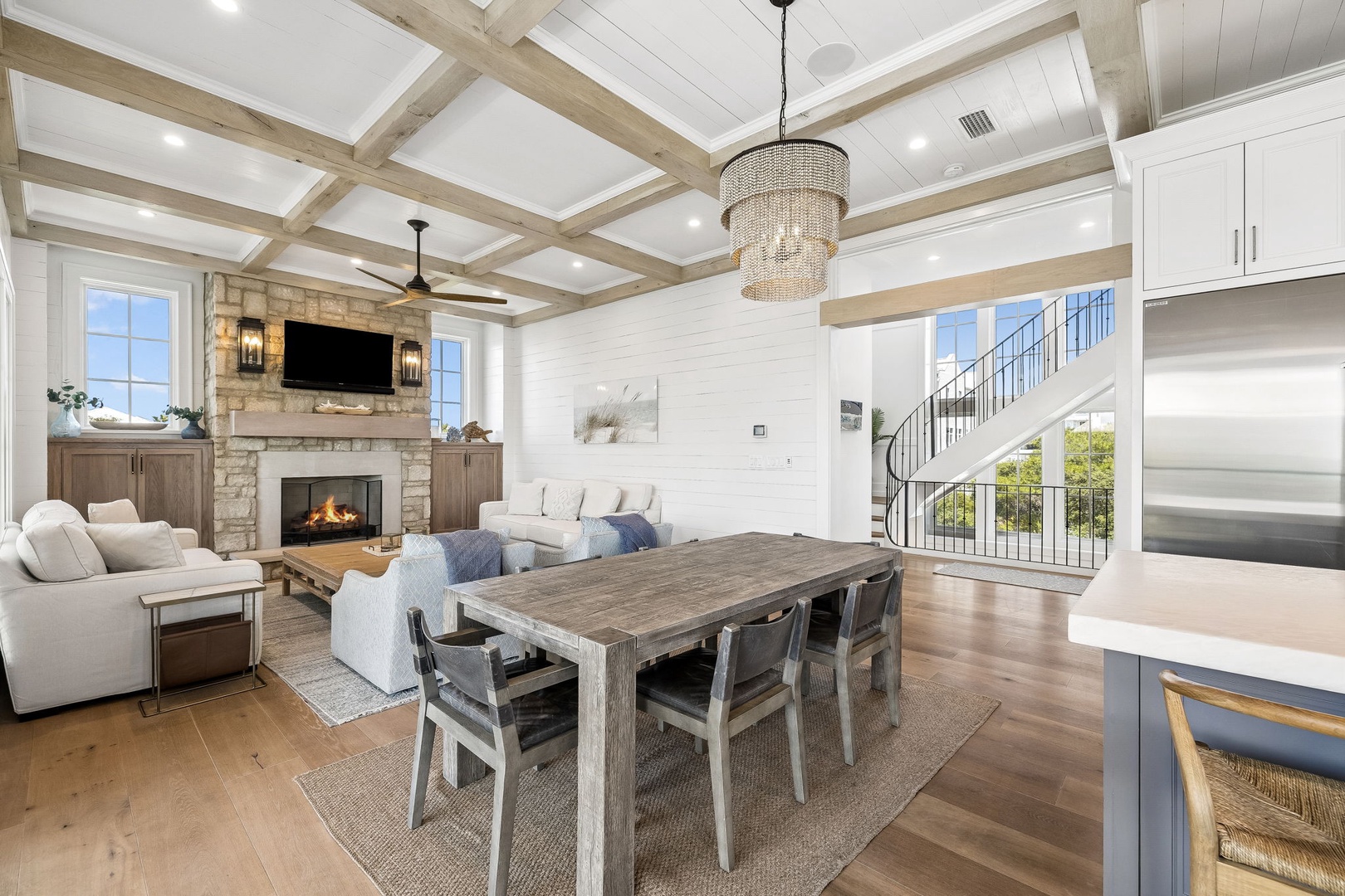 Step into your vacation sanctuary where soaring beamed ceilings and an elegant chandelier set the stage for memorable gatherings around the dining table, while a crackling fireplace invites cozy evenings in your stylish open-plan retreat.