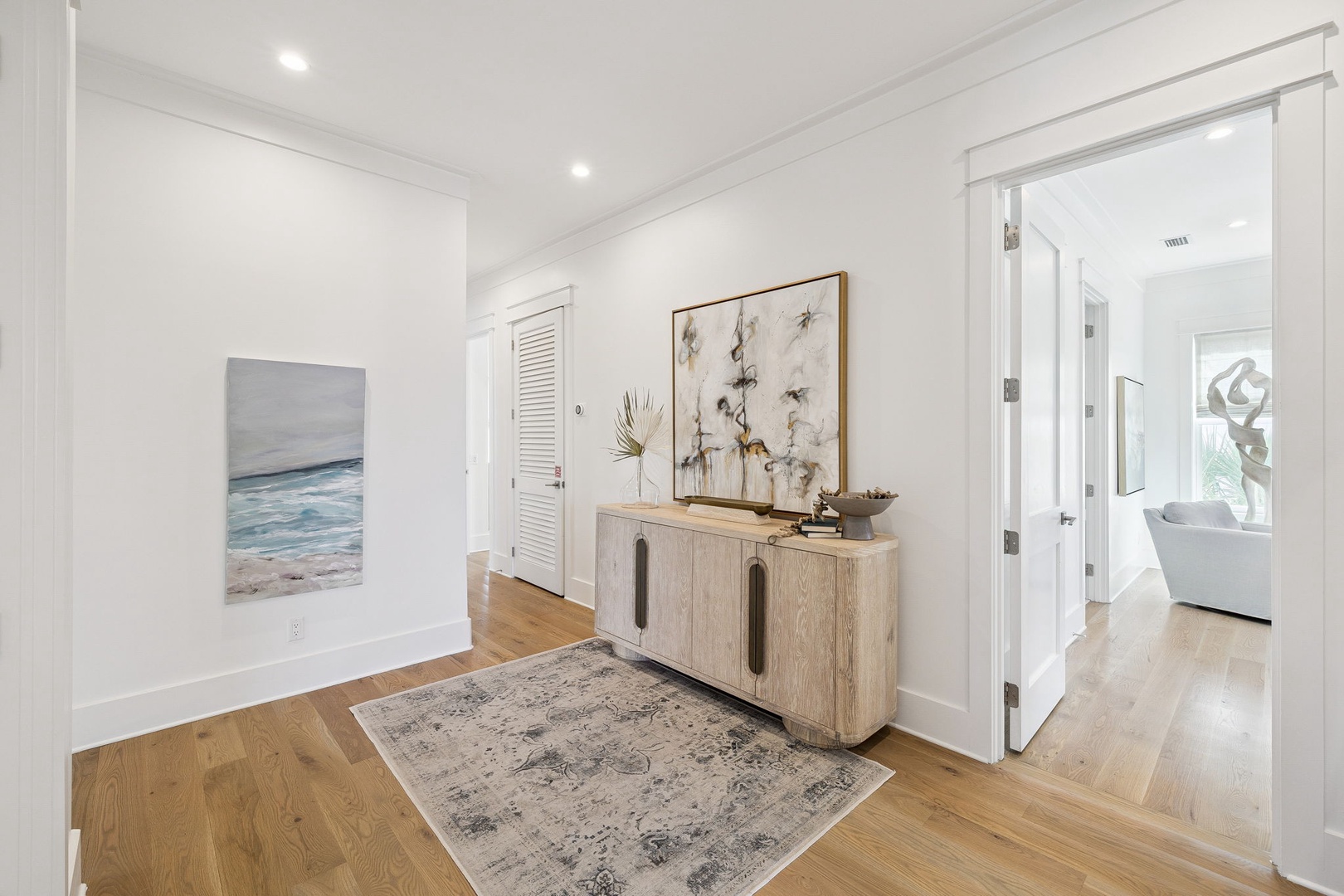 Step into your elegant foyer where coastal artwork and warm hardwood floors create an instant sense of home and tranquility.