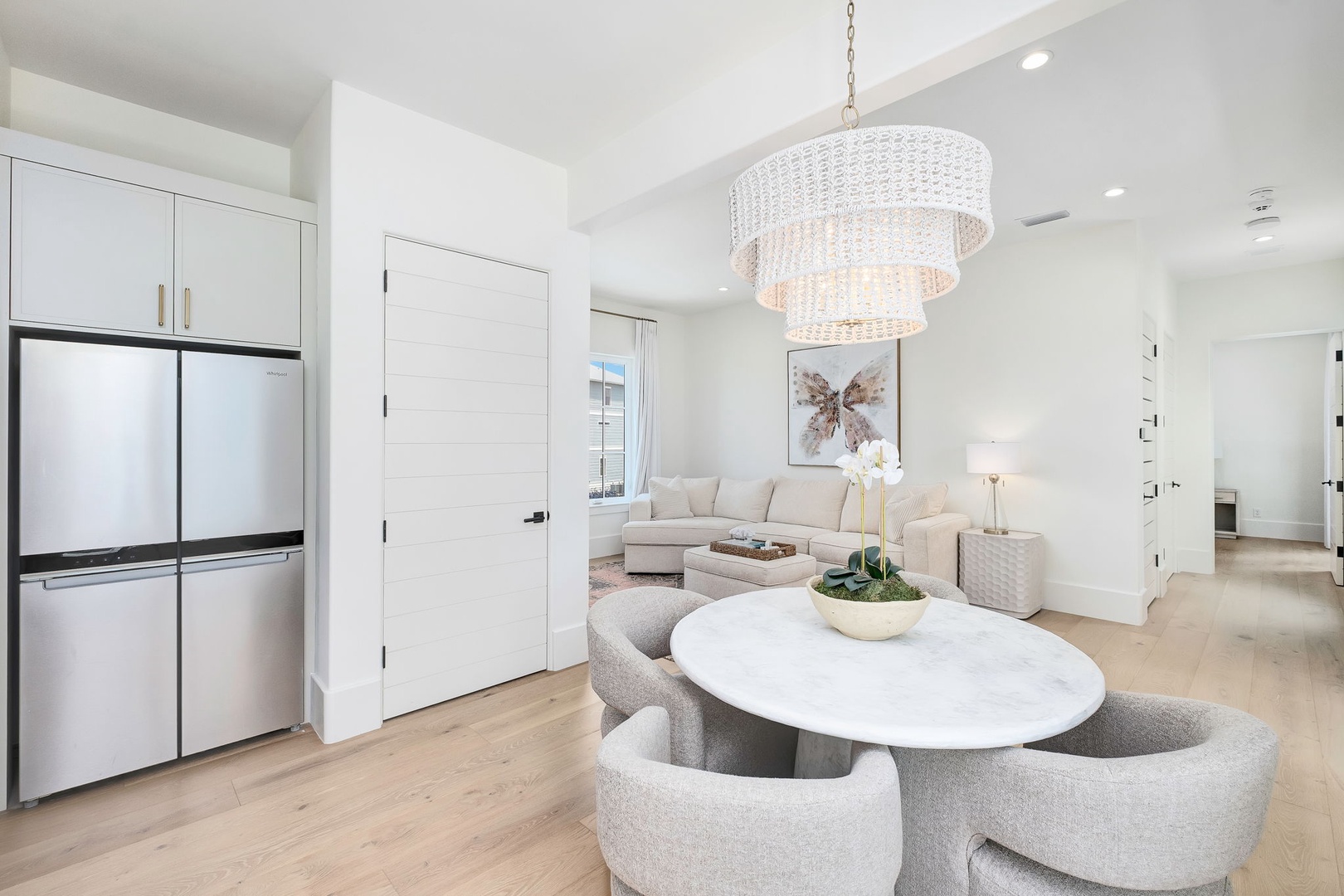 Step into a serene, light-filled space where modern elegance meets comfort. Gather around the sleek marble dining table or relax on the plush sectional under a dazzling chandelier—your perfect retreat awaits.