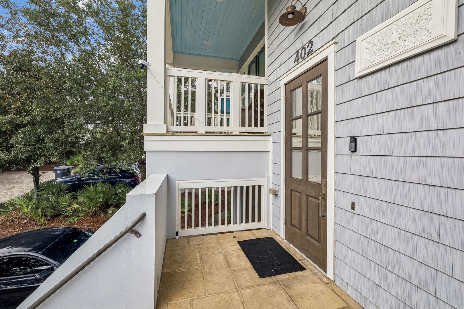 The property entrance at unit 402 welcomes you with coastal charm—white railings, soft blue porch ceilings, and natural light creating a bright, airy arrival.