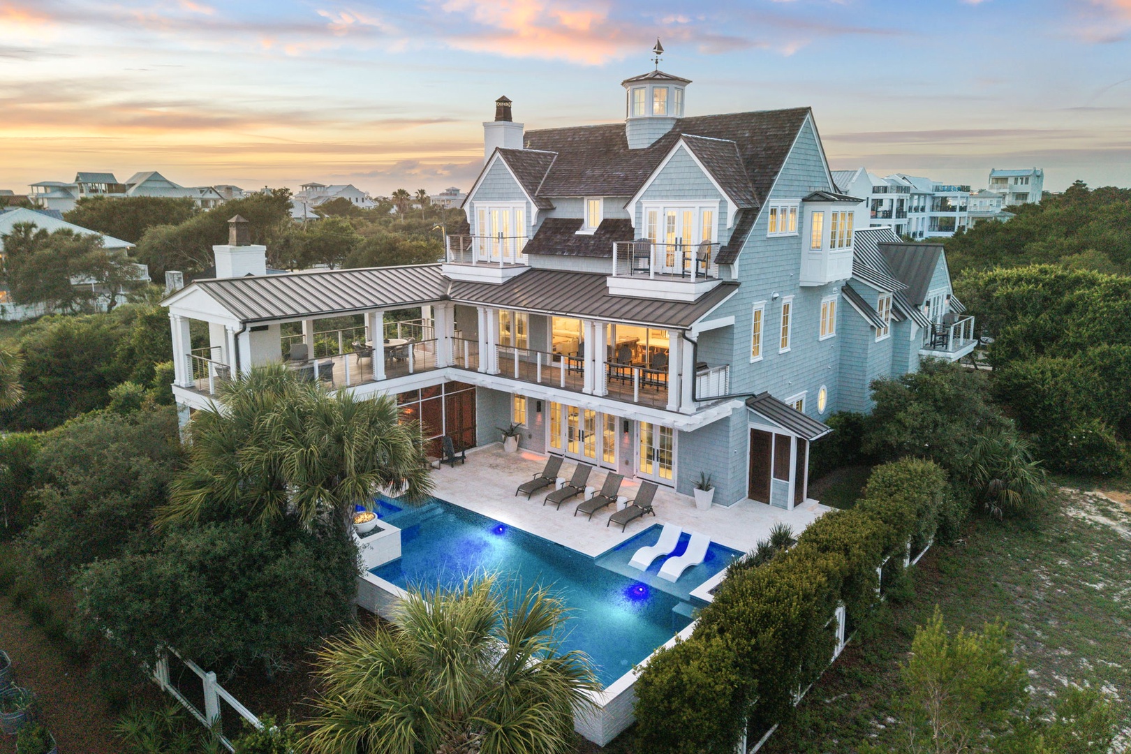 A stunning coastal retreat with multiple stories, a private pool with lounge chairs, and spacious balconies surrounded by lush tropical vegetation and ocean breezes.