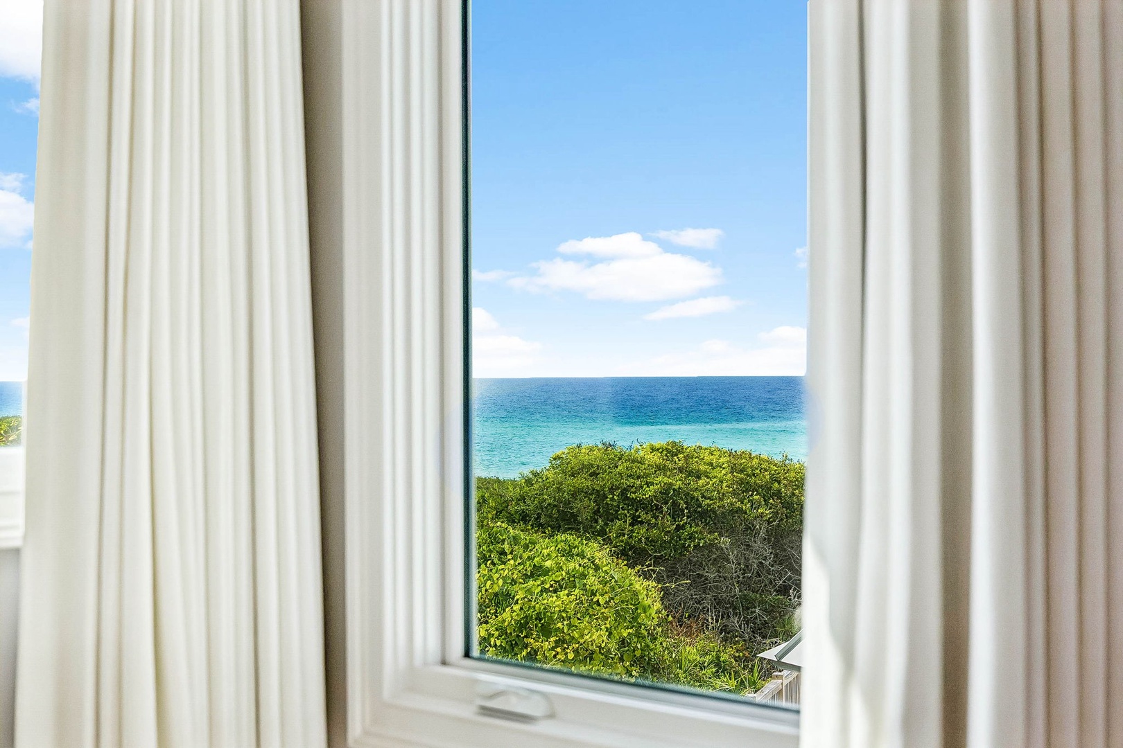 Wake up to stunning ocean views framed by lush coastal greenery under clear blue skies—your window to paradise awaits.