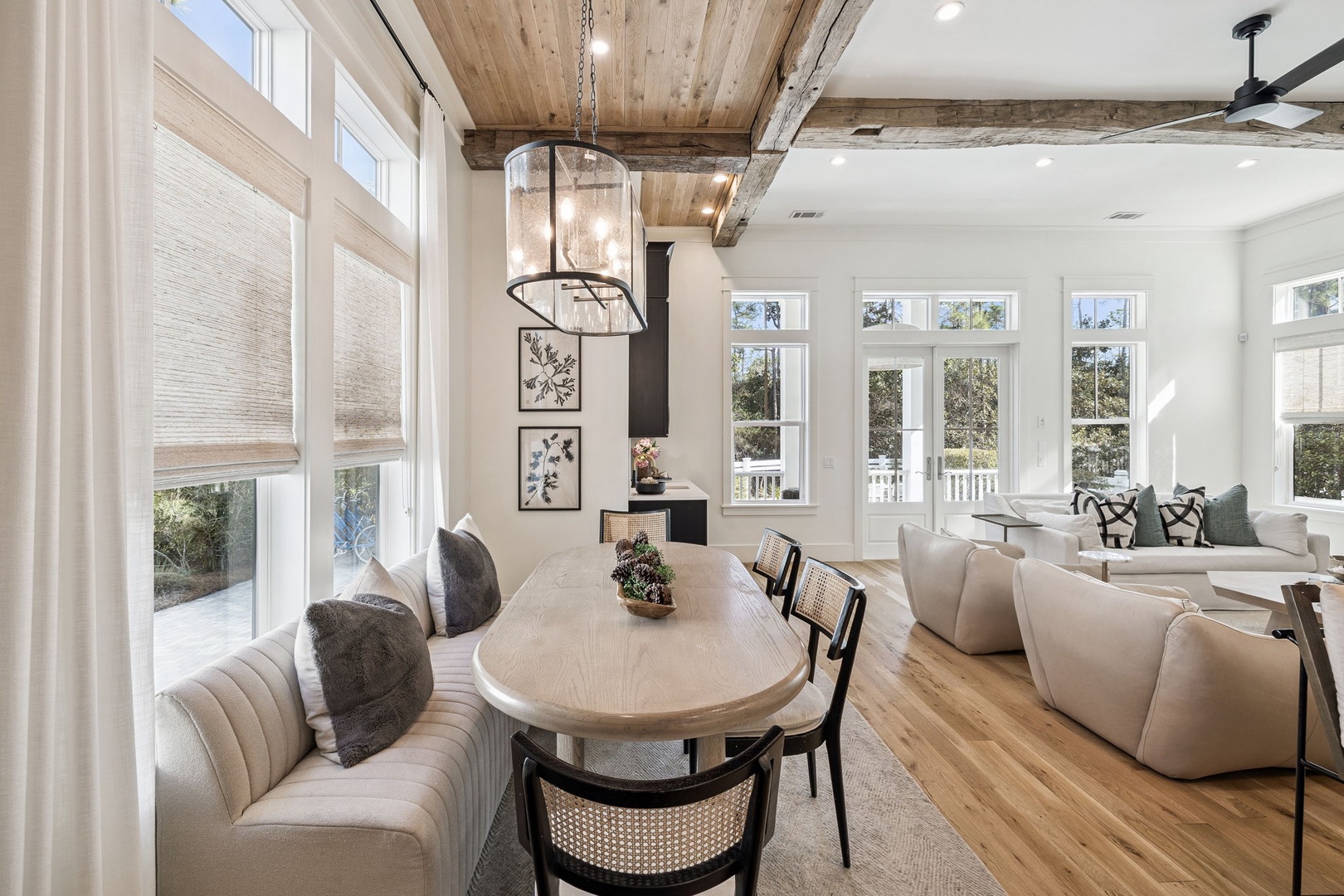 Gather around your elegant dining table beneath rustic beams, where natural light floods through expansive windows creating perfect moments for memorable meals.