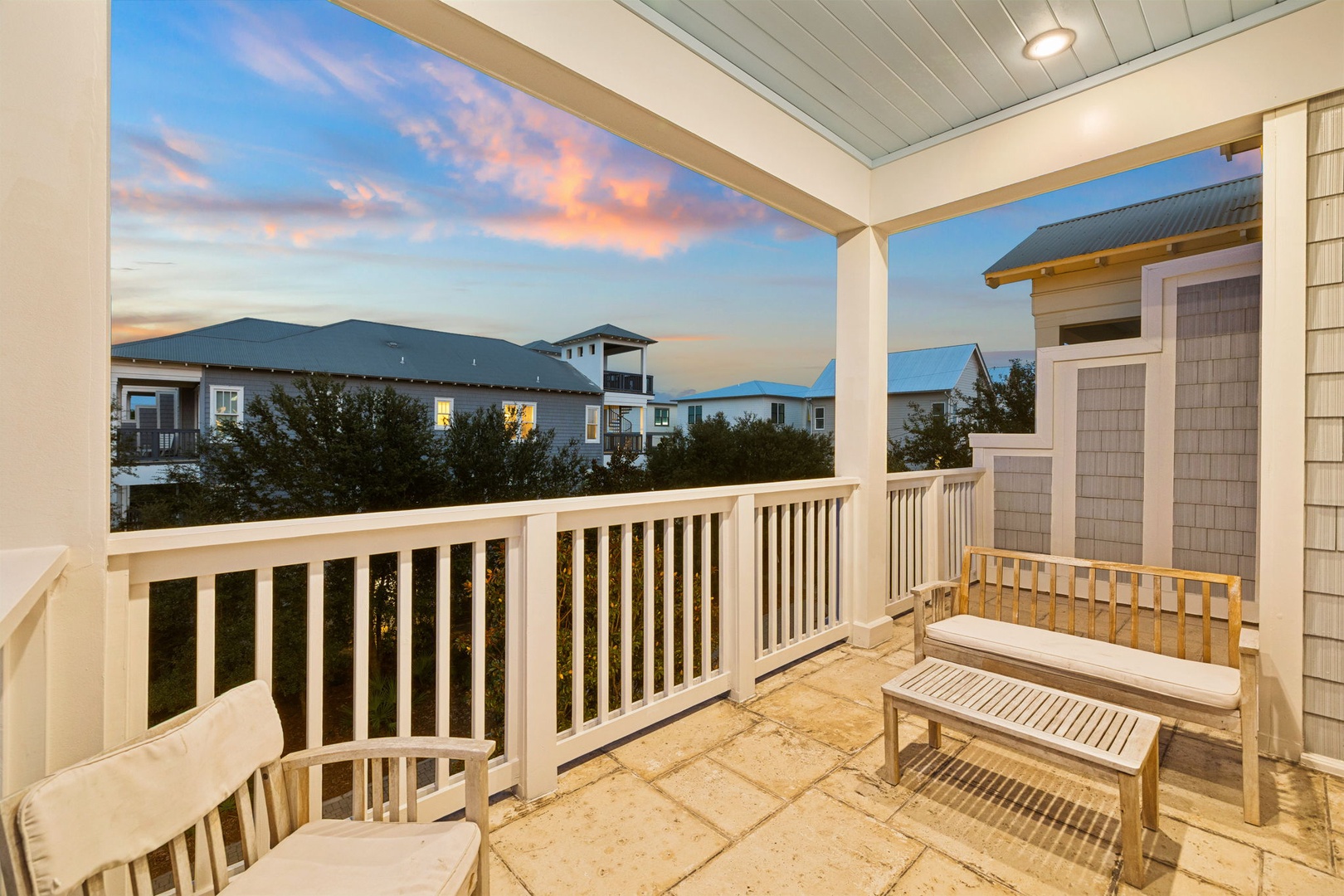 The property is part of a charming coastal neighborhood, surrounded by similar architecture and nearby homes, with colorful evening skies adding to the setting's tranquil ambiance.