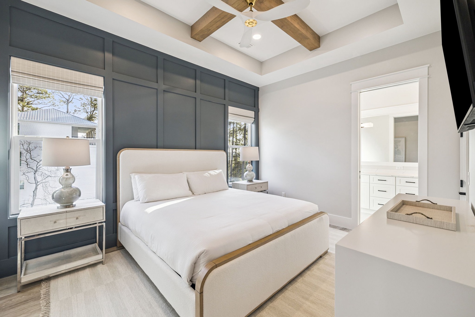 Your serene bedroom retreat features crisp white linens, exposed ceiling beams, and elegant navy accents that create the perfect sanctuary for rest.