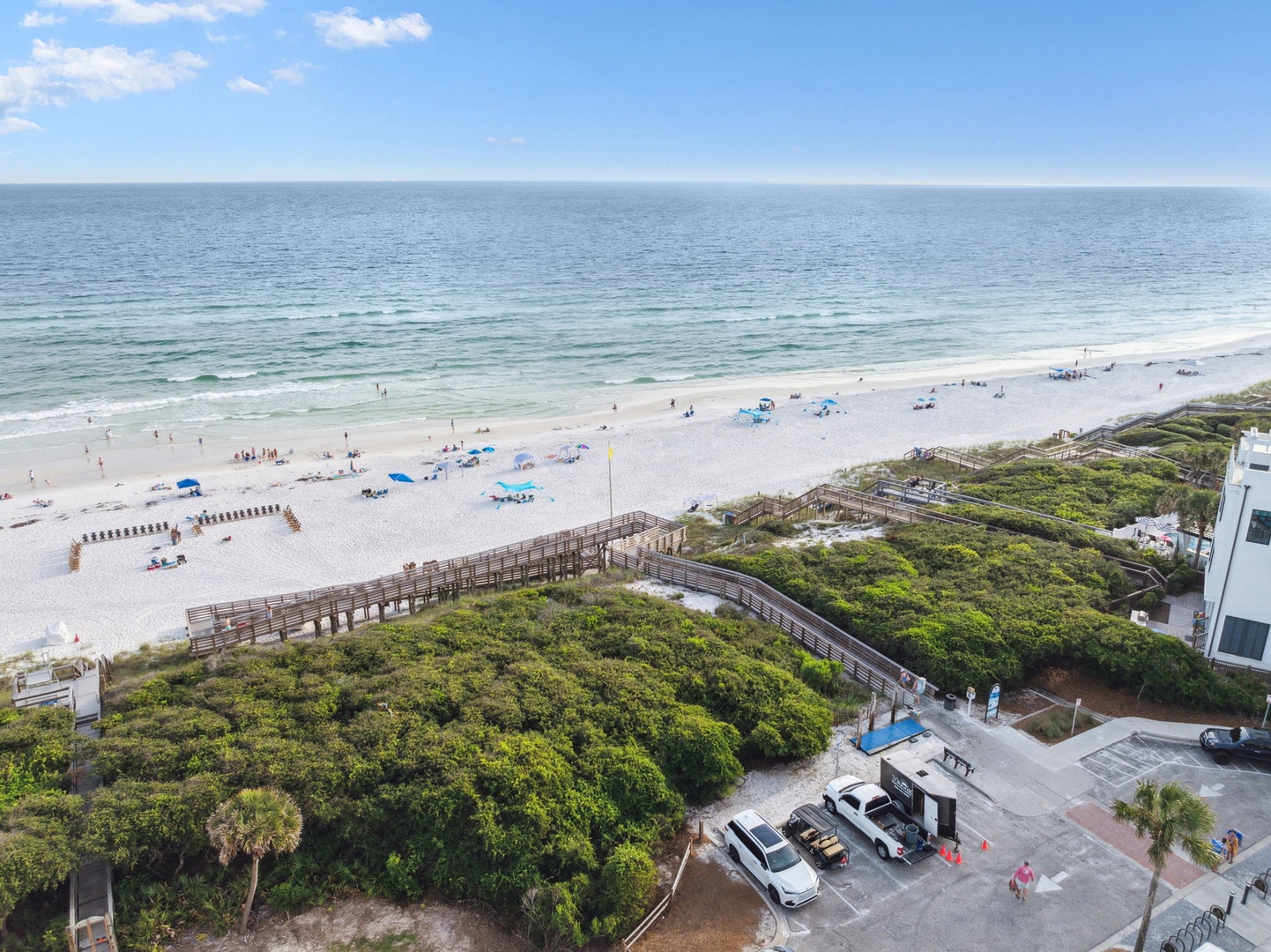 Beautiful white sand beach with pristine waters and wooden boardwalk access through natural coastal vegetation.