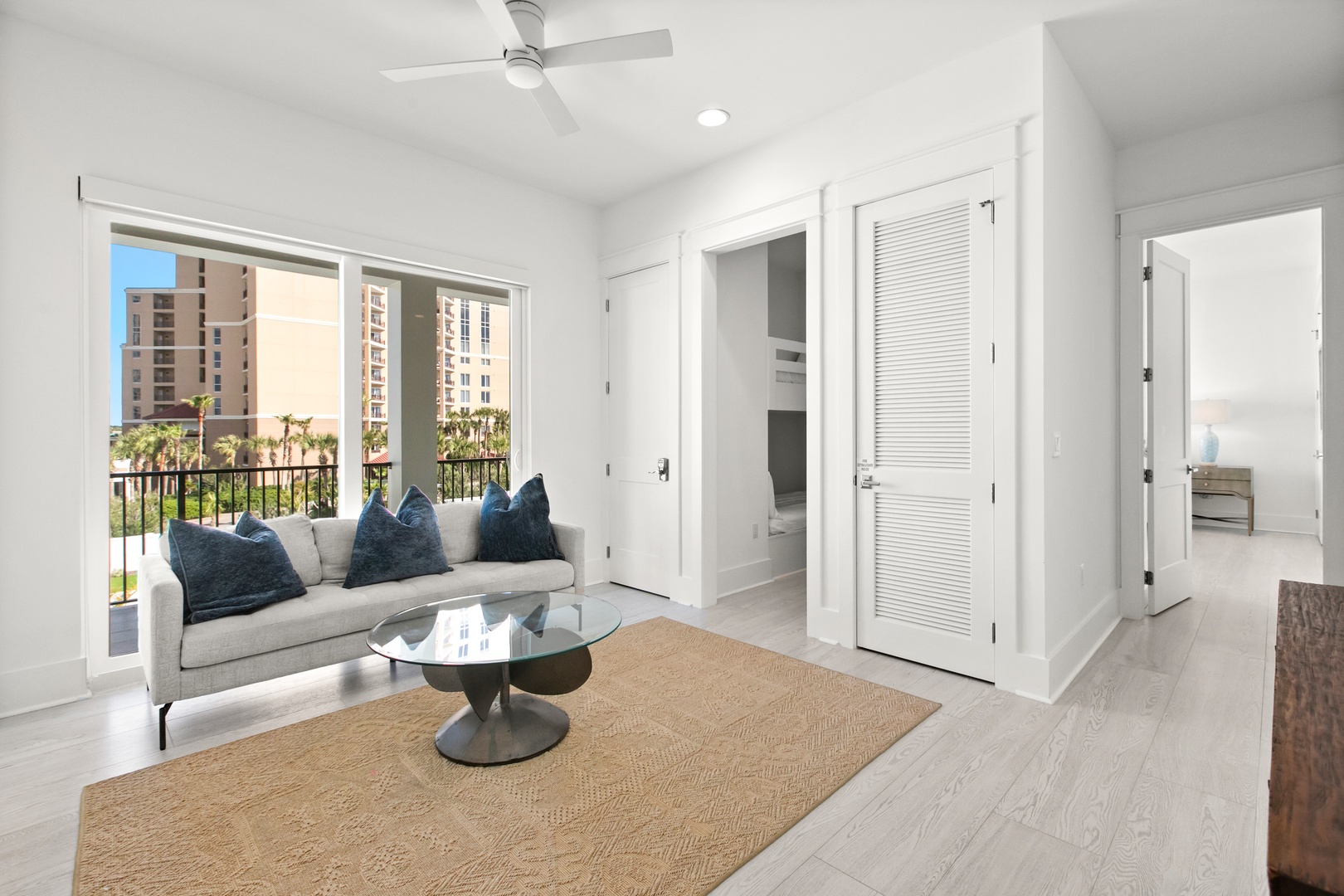 Settle into your bright living space where a gentle breeze flows through from the balcony. Relax on the cozy sofa with views of palm trees and sunshine, and enjoy the calm, open atmosphere that makes every moment feel like a getaway.