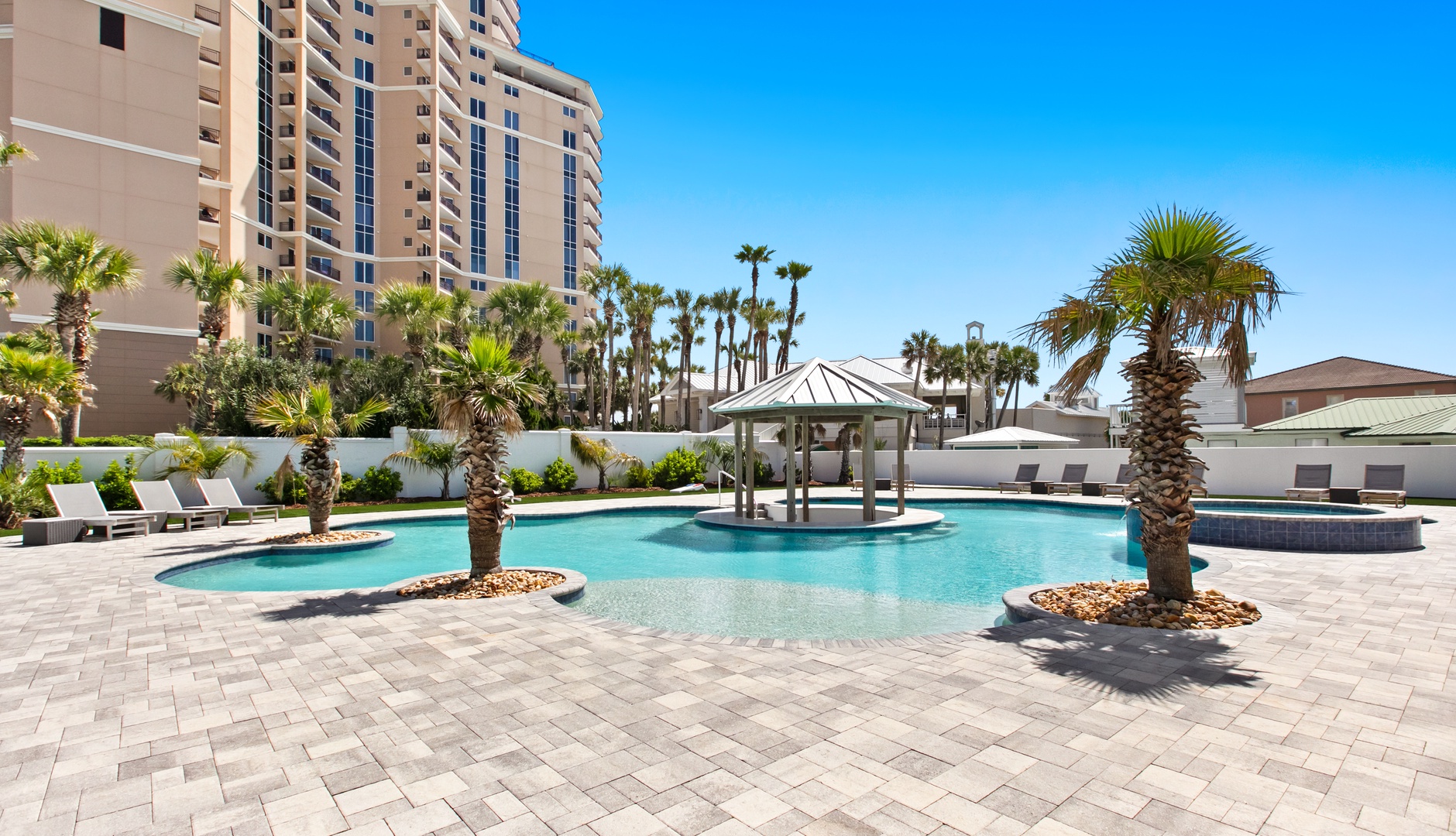 This resort-style pool offers a tropical escape under sunny skies, complete with palm trees, a shaded cabana, and a bubbling hot tub—perfect for relaxation or soaking up the sun.