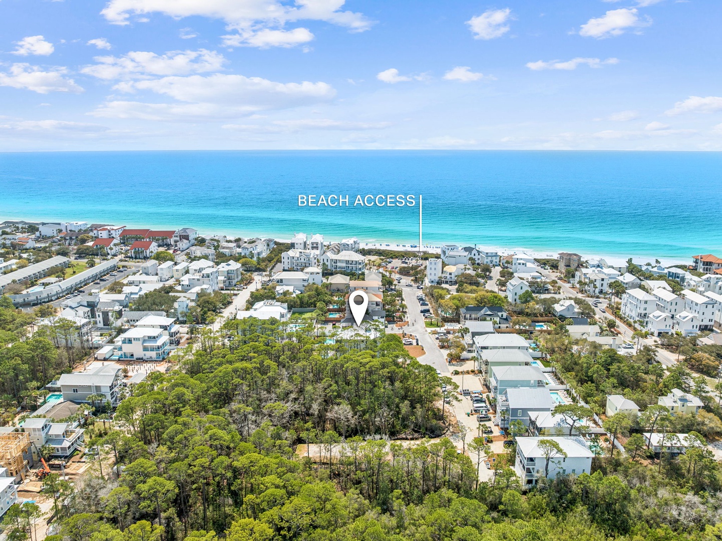 Aerial view of a coastal community nestled among lush greenery, with direct beach access just steps from pristine turquoise waters and white sand shores.