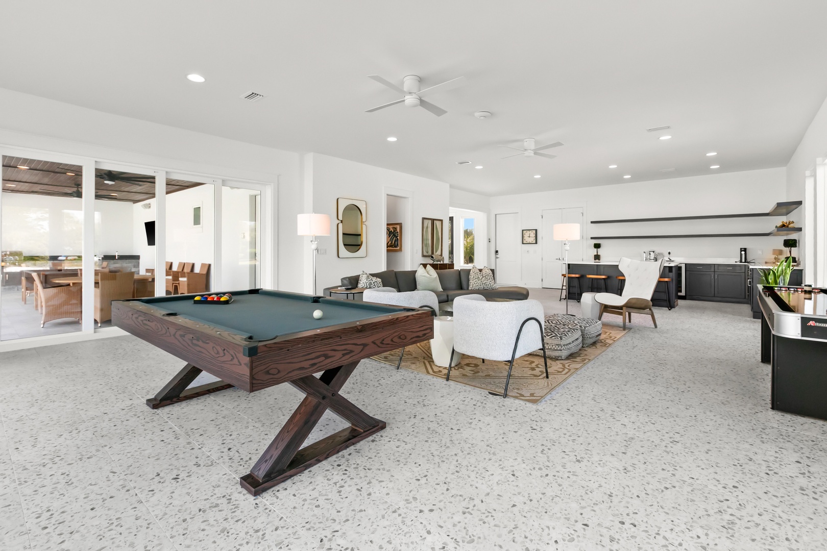 Step into your open-concept living space where a billiards table invites friendly competition, plush seating beckons relaxation, and modern style meets comfort under soaring ceilings with ceiling fans that keep you cool year-round.