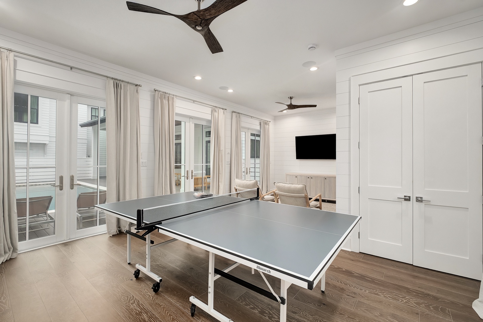 Your private game room awaits with ping pong table, wall-mounted TV, and elegant seating for hours of fun.