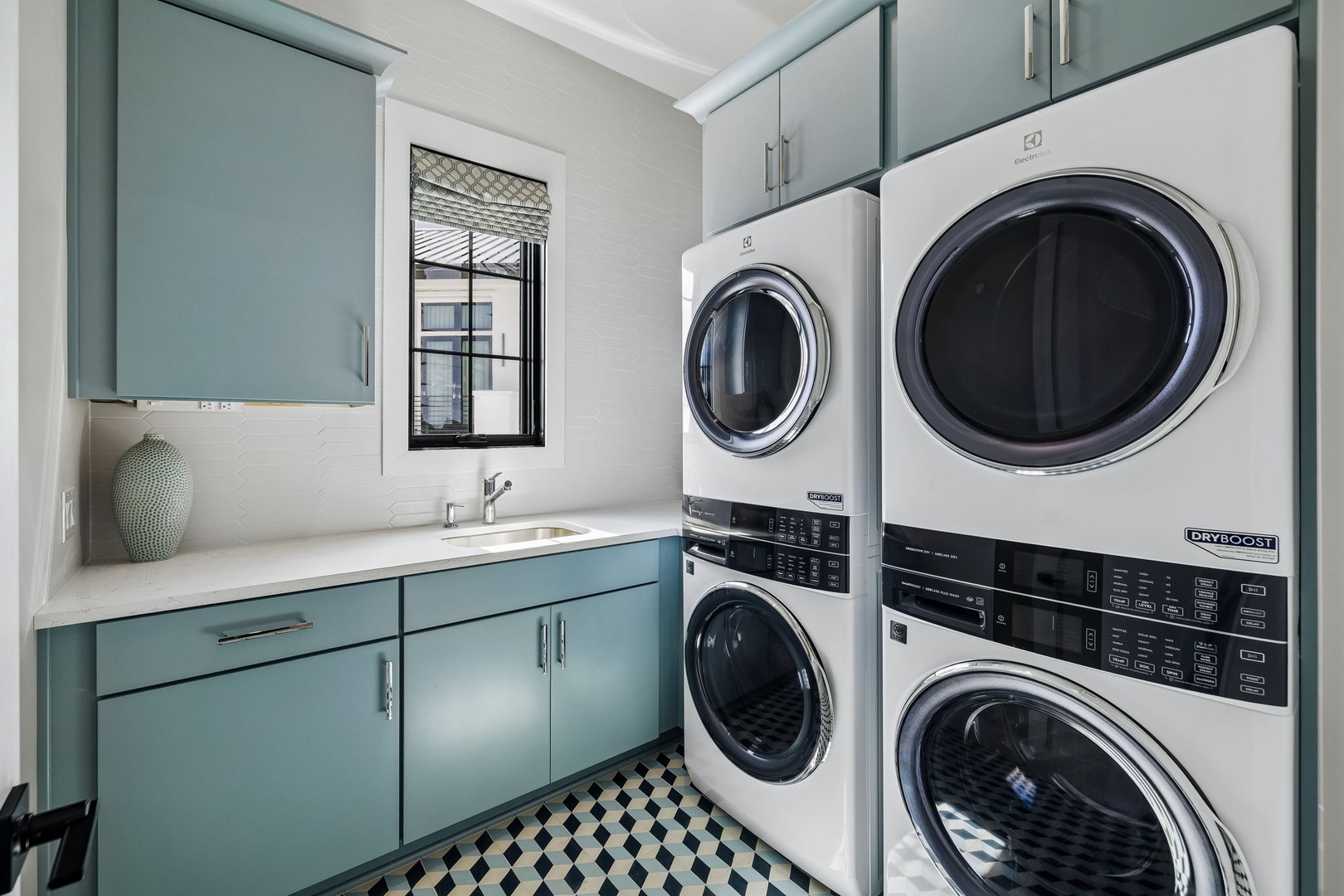 Your own in-unit laundry room with stacked washer and dryer, stylish blue cabinetry, and abundant storage—making long stays effortless and comfortable.