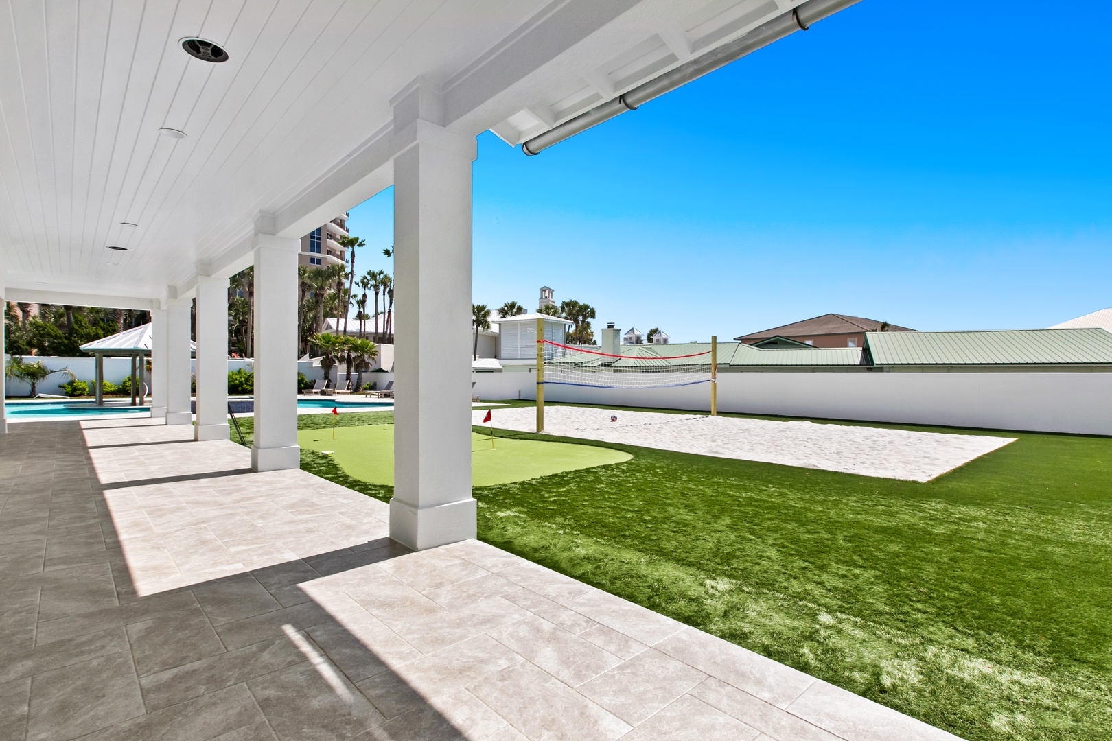 Covered patio opens to a private recreation area featuring artificial turf, volleyball court, and sparkling pool—perfect for friendly competition and sunny California days.