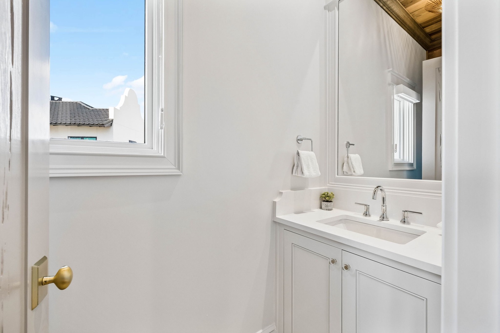 Freshen up in this bright, pristine bathroom with a sleek vanity, soft towels, and crisp natural light flooding through the window—a perfect space to start or end your day feeling refreshed.