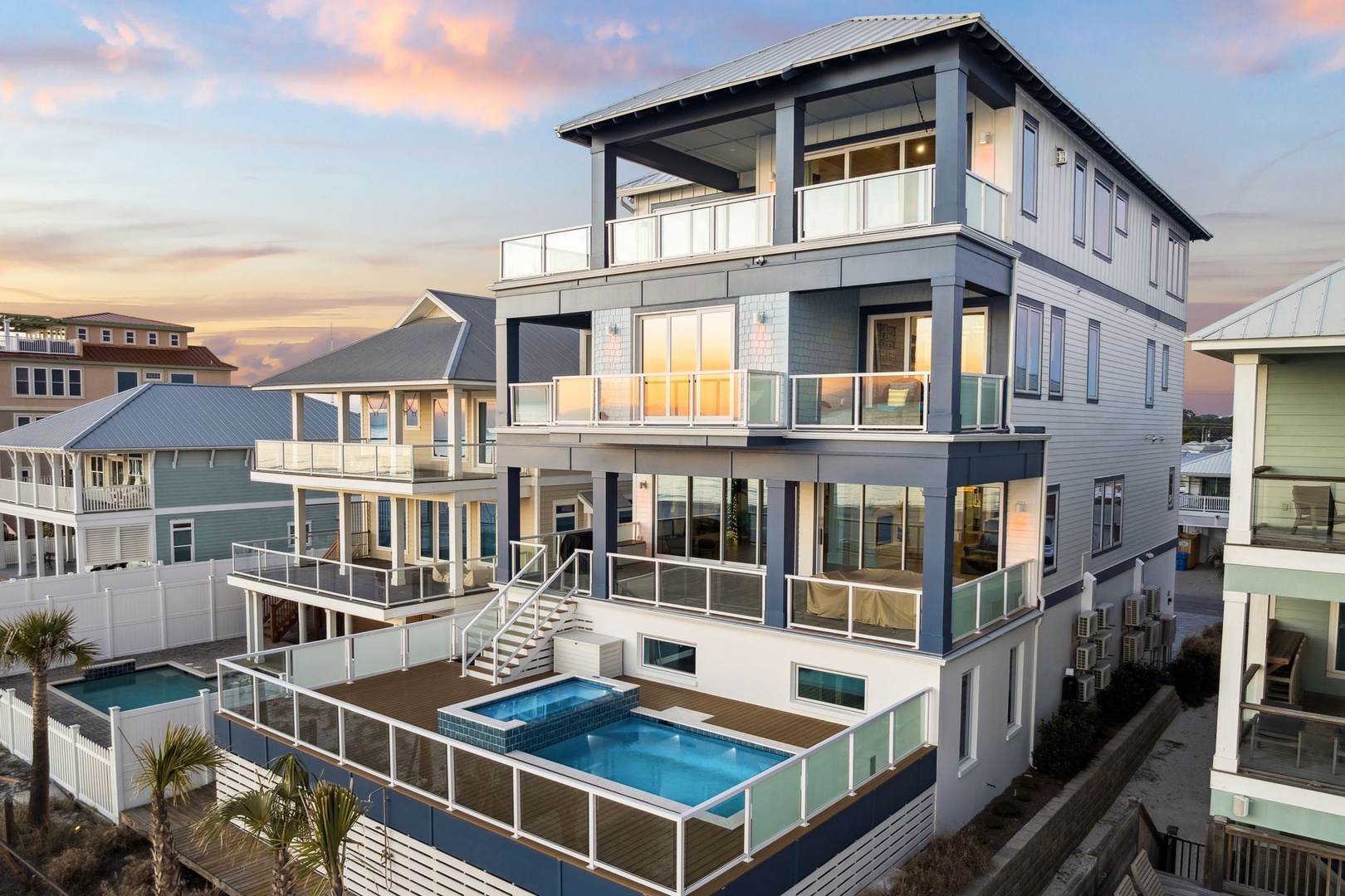 Stunning modern beachfront home with multiple balconies and private pool captures golden sunset views in this coastal neighborhood.