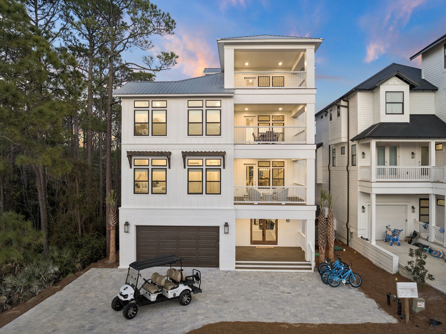Modern three-story coastal home with spacious balconies, surrounded by lush pine trees and featuring convenient golf cart and bike access.