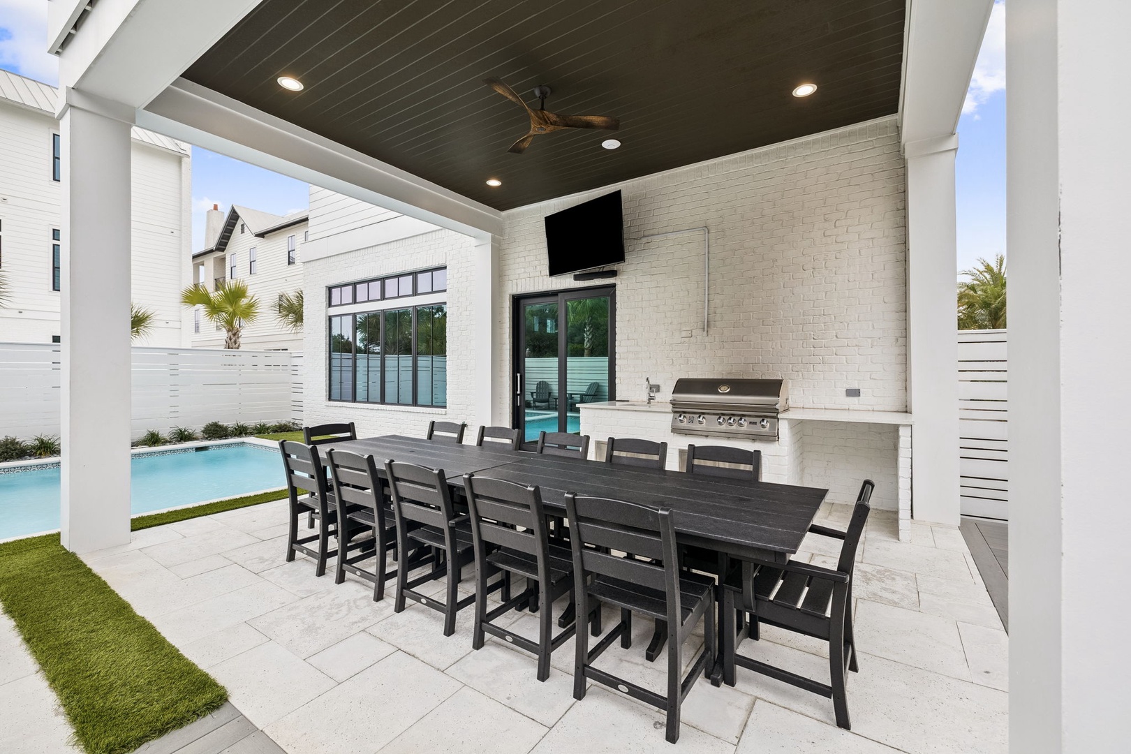 Your outdoor dining oasis awaits with seating for ten under a stylish covered patio, complete with grilling station and pool views.