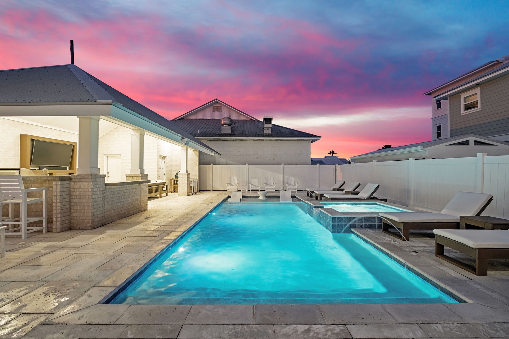 Spectacular sunset paints the sky in brilliant pinks and purples above this private pool oasis in a coastal neighborhood setting.