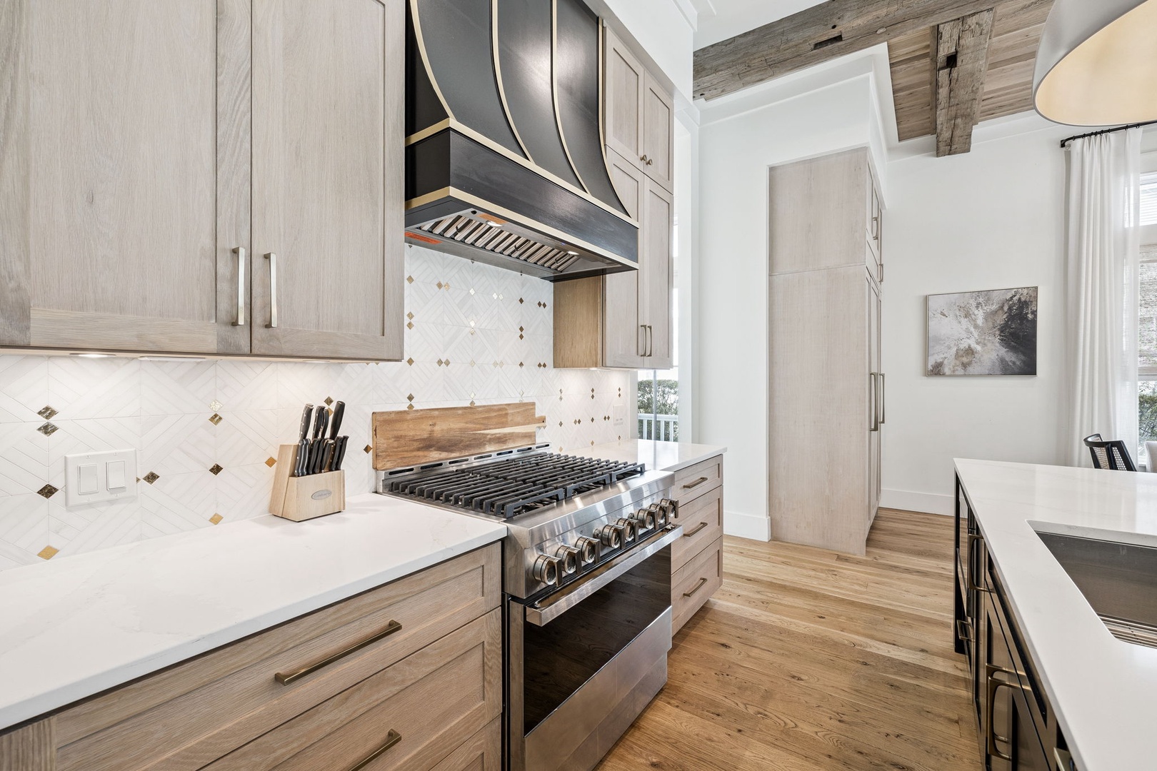 Step into your gourmet kitchen featuring professional-grade gas range, custom cabinetry, and beautiful tile backsplash for memorable meal preparation.