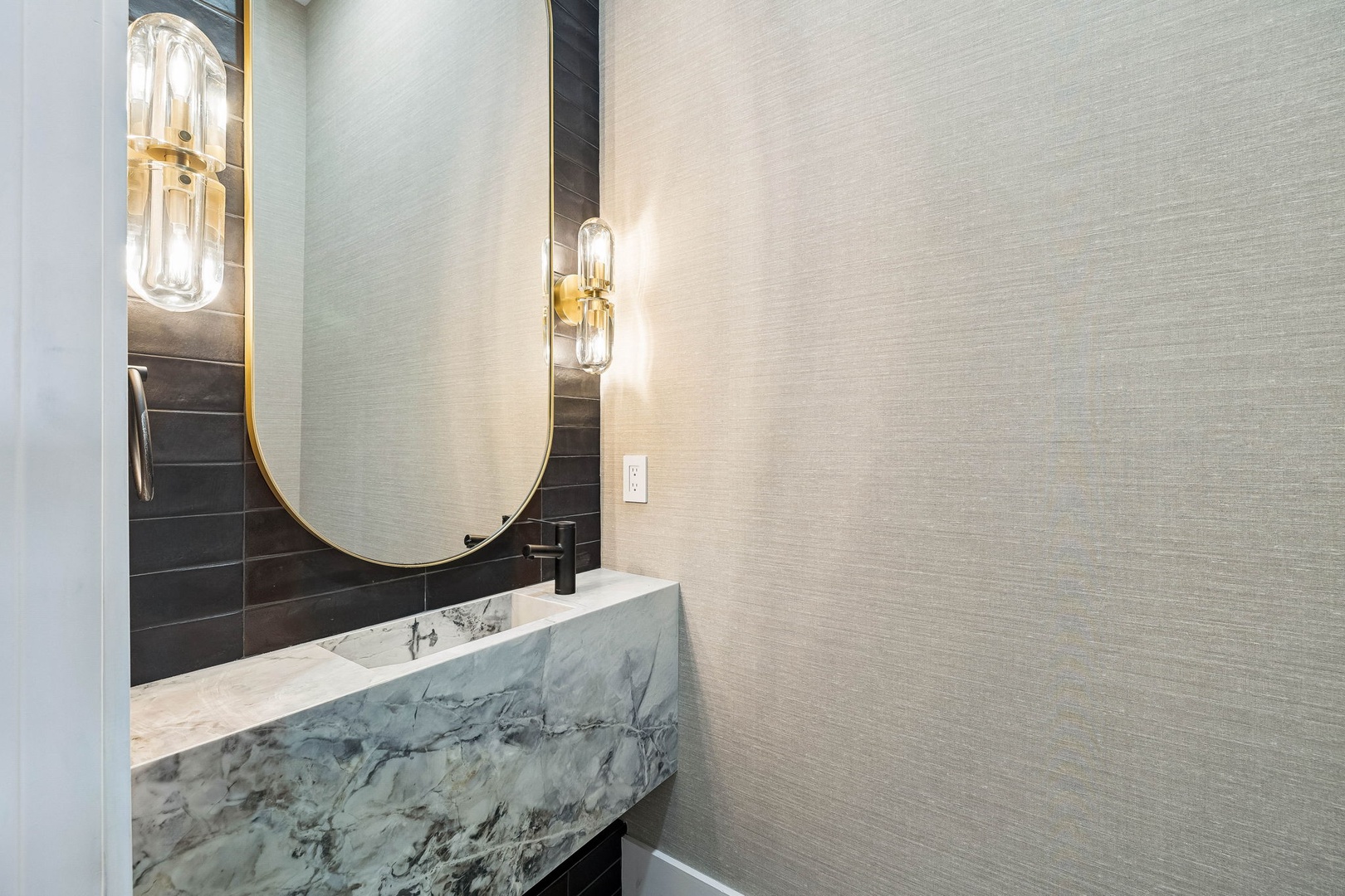 Step into your elegantly appointed bathroom where sophisticated style meets modern comfort. The striking marble vanity, gold-framed mirror, and designer lighting create a refined space that feels both luxurious and welcoming.
