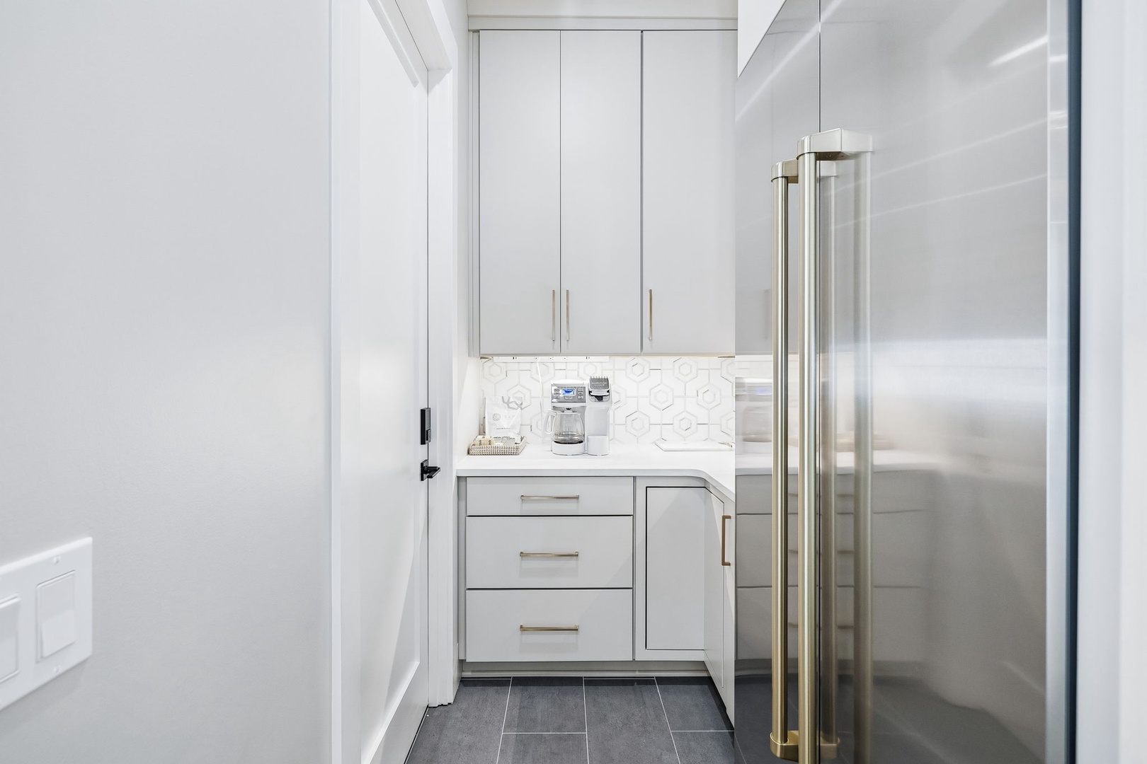 Step into your sleek butler's pantry, where crisp white cabinetry, gleaming counters, and top-notch appliances make entertaining a breeze.