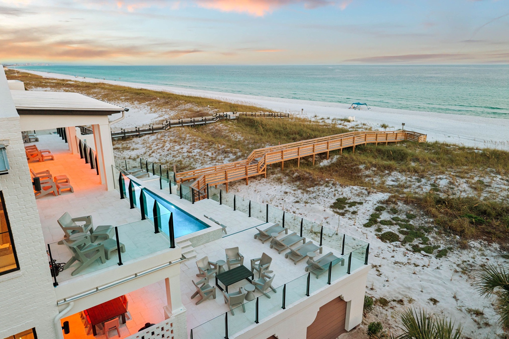 Stunning beachfront property with private boardwalk leading to pristine white sand and turquoise waters, featuring a pool and spacious outdoor decks for your ultimate coastal escape.