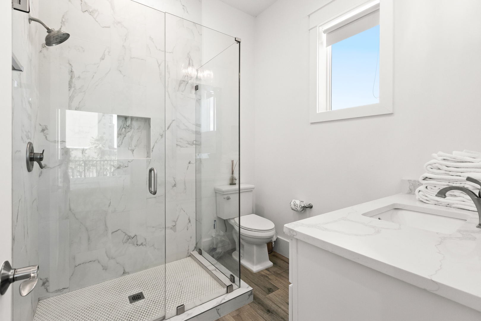 Step into your private spa-like bathroom with marble accents, a sleek glass-enclosed shower, and soft white finishes—your perfect retreat after a day of adventure.