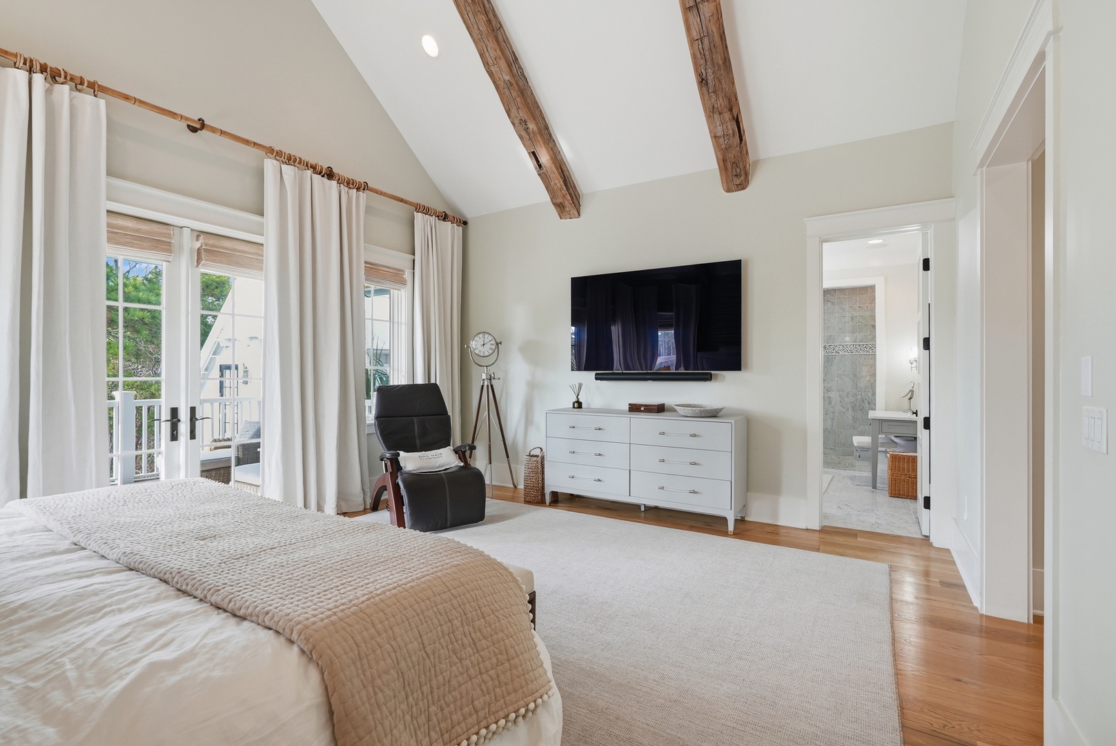 Unwind in your spacious master suite, where rustic beams meet modern comfort. Natural light pours through doors to your private balcony while your ensuite awaits.
