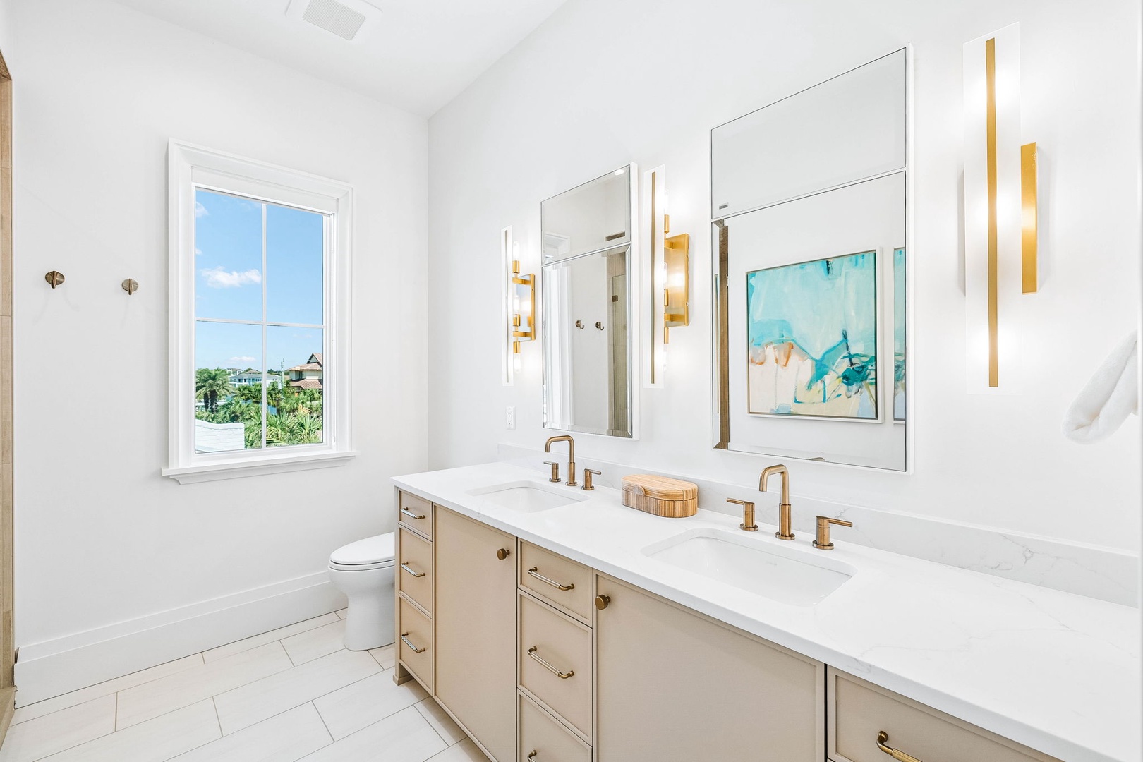 Step into your spa-like bathroom with dual vanities, elegant gold fixtures, and bright natural light. The sleek marble countertops and contemporary design create a refreshing retreat where you can unwind in style.