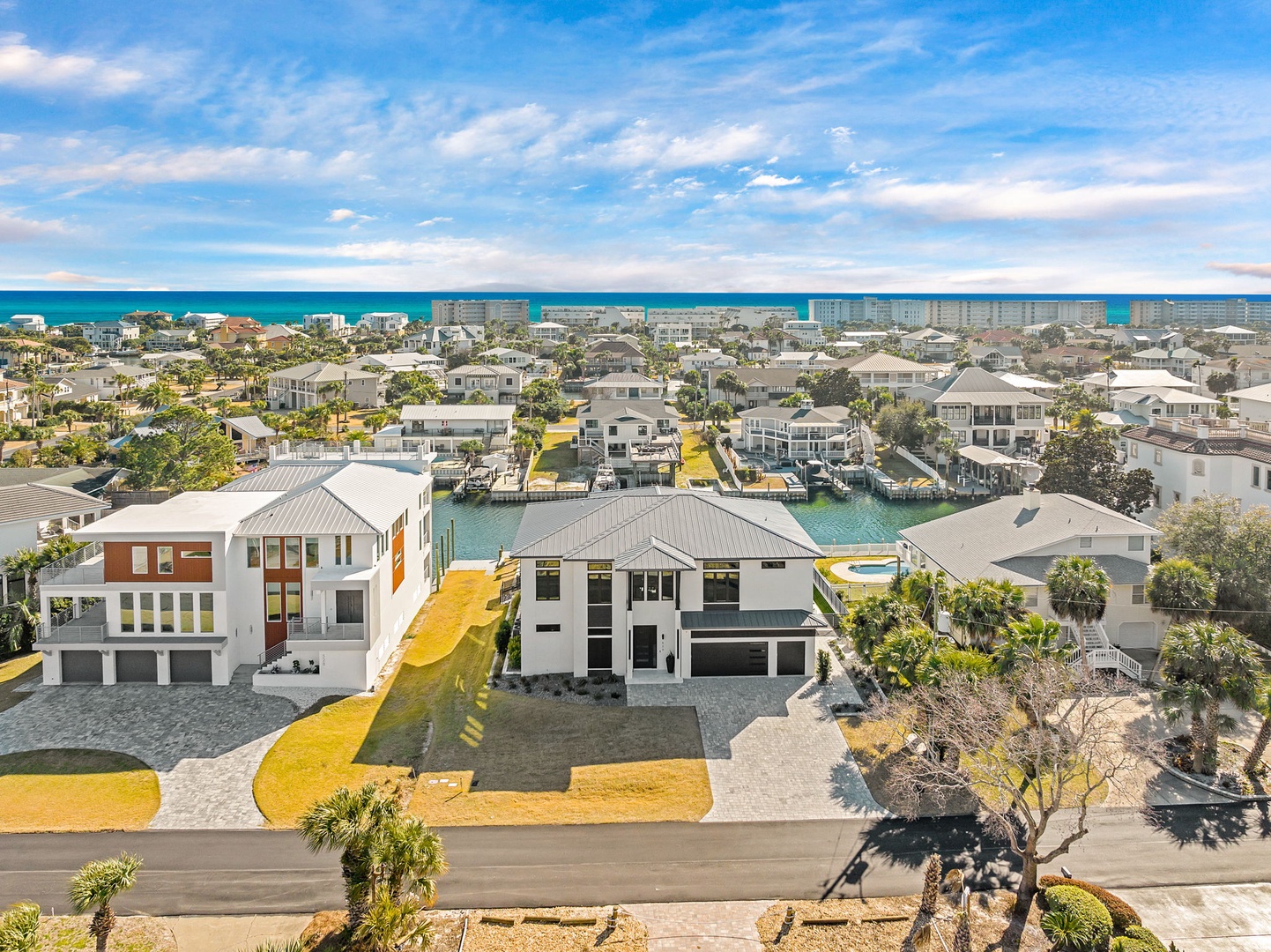 Aerial view of modern beachfront vacation home with canal access and stunning ocean proximity in coastal neighborhood.