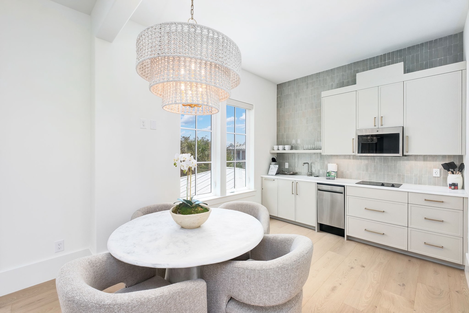 Dine in style beneath an elegant chandelier while enjoying your fully equipped kitchen with modern appliances and a sleek glass tile backsplash.
