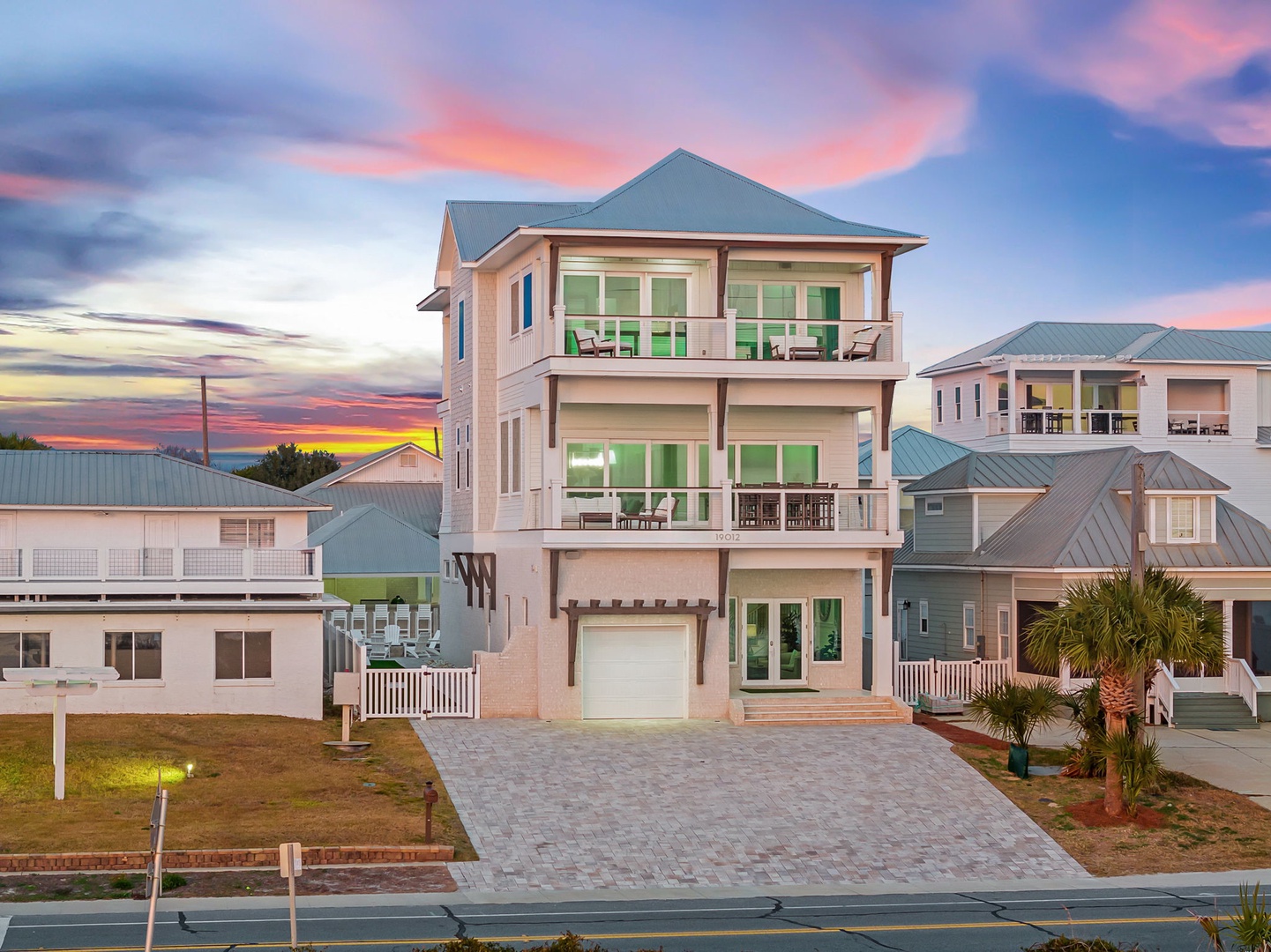 Stunning three-story beachfront home with multiple balconies and large windows, perfectly positioned in a coastal neighborhood.