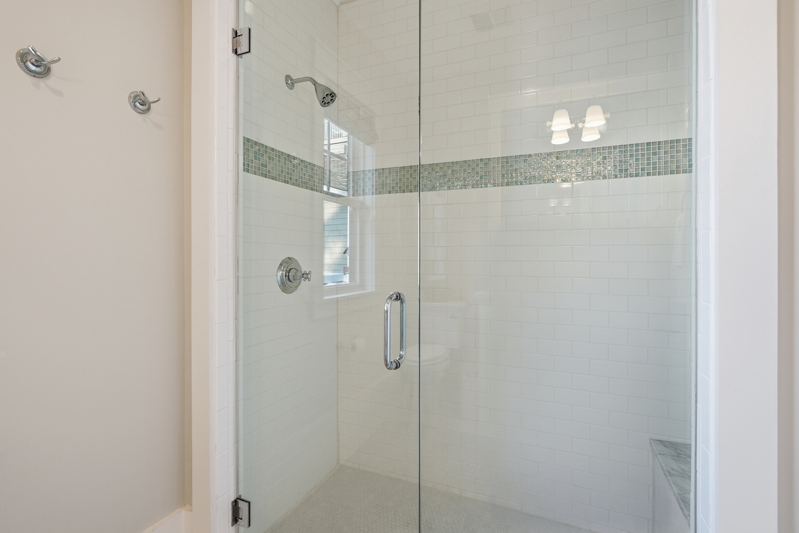 Step into your private glass-enclosed shower featuring elegant subway tile walls and a sparkling mosaic accent stripe that adds a spa-like touch to your daily routine.