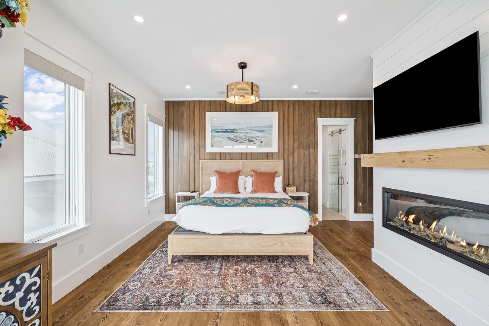 Unwind in your serene bedroom with warm wood accents, cozy fireplace, and natural light streaming through large windows.