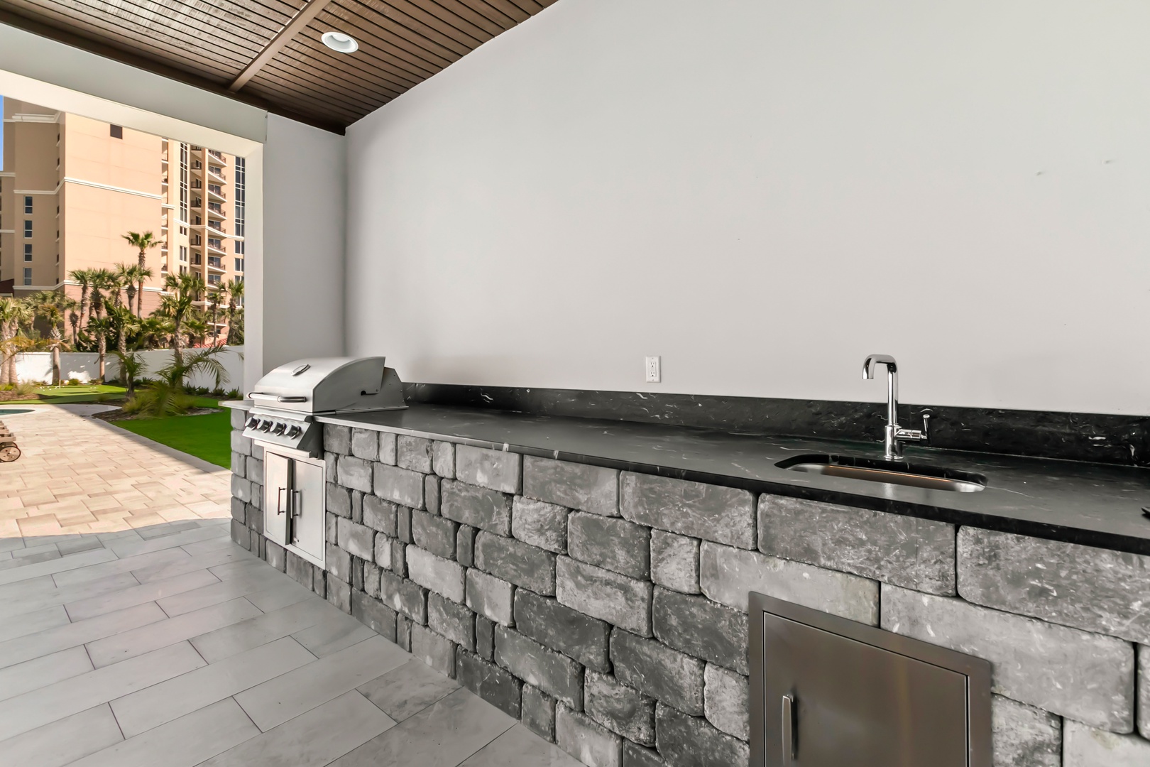 Fire up the grill on your private covered patio, complete with a sleek outdoor kitchen featuring polished countertops and a modern sink—perfect for preparing meals in the fresh air.