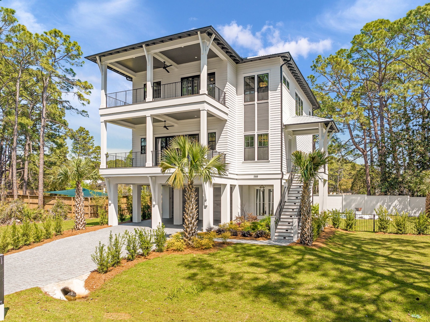 Modern coastal home featuring spacious balconies, lush landscaping with palm trees, and plenty of natural light throughout this three-story retreat.