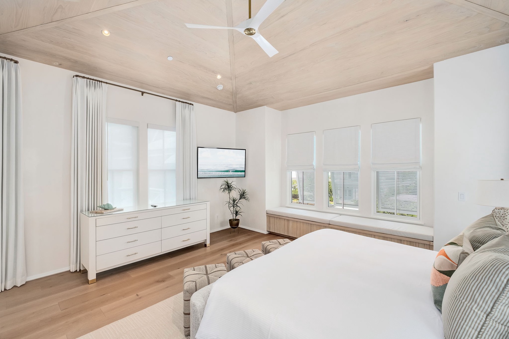 Step into your serene bedroom retreat with a calming coastal palette and natural wood tones. Soft breezes from the ceiling fan, ocean views through your windows, and a plush bed await—your peaceful escape after sunny beach days.