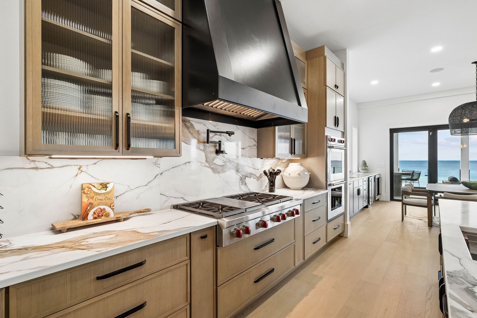 Picture yourself cooking in this elegant kitchen with marble countertops, professional appliances, and stunning ocean views just beyond the glass doors—your own slice of coastal paradise.