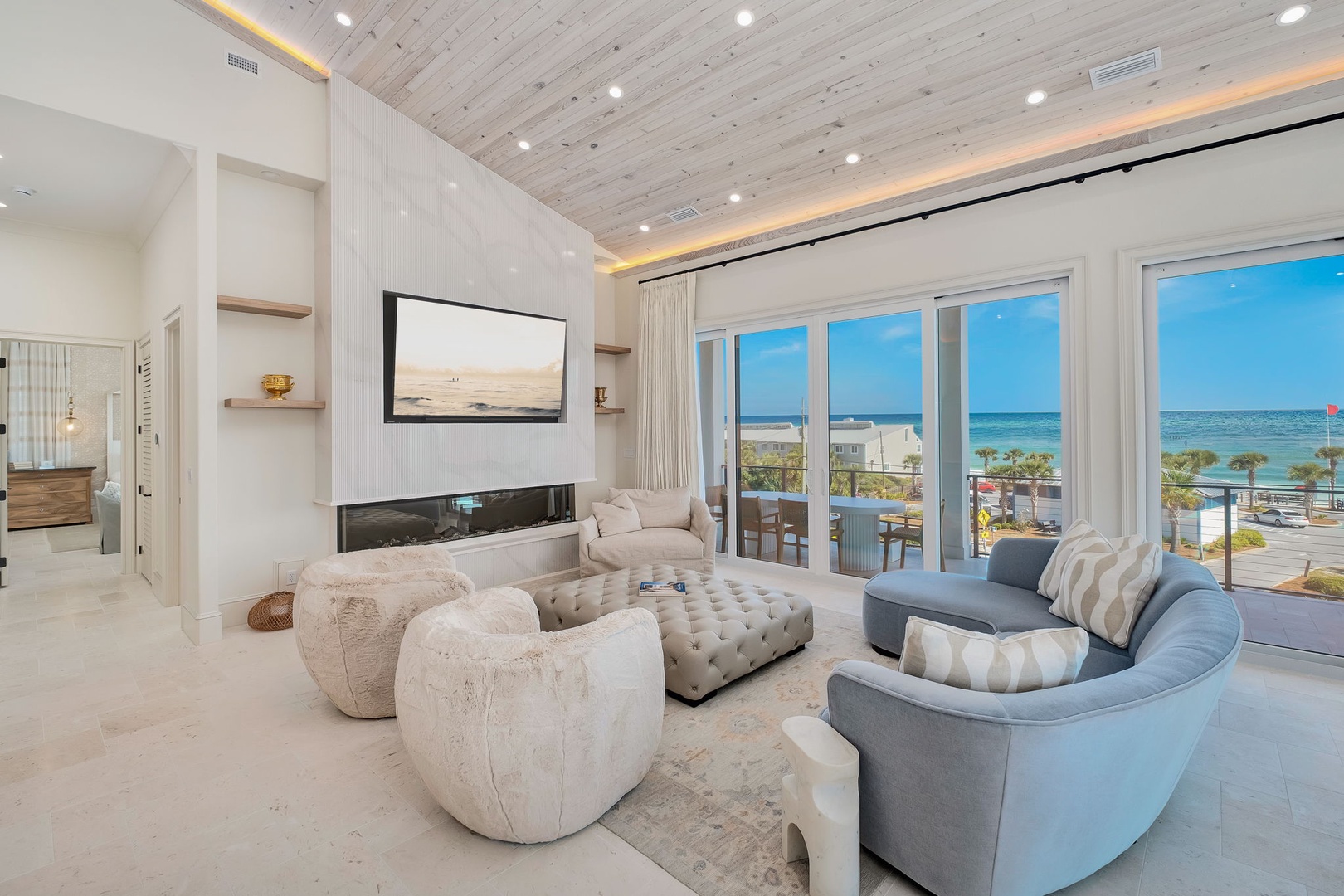 You'll love the soaring wood-beamed ceiling and floor-to-ceiling windows framing stunning ocean views. Sink into plush seating by the cozy fireplace, your perfect coastal retreat.