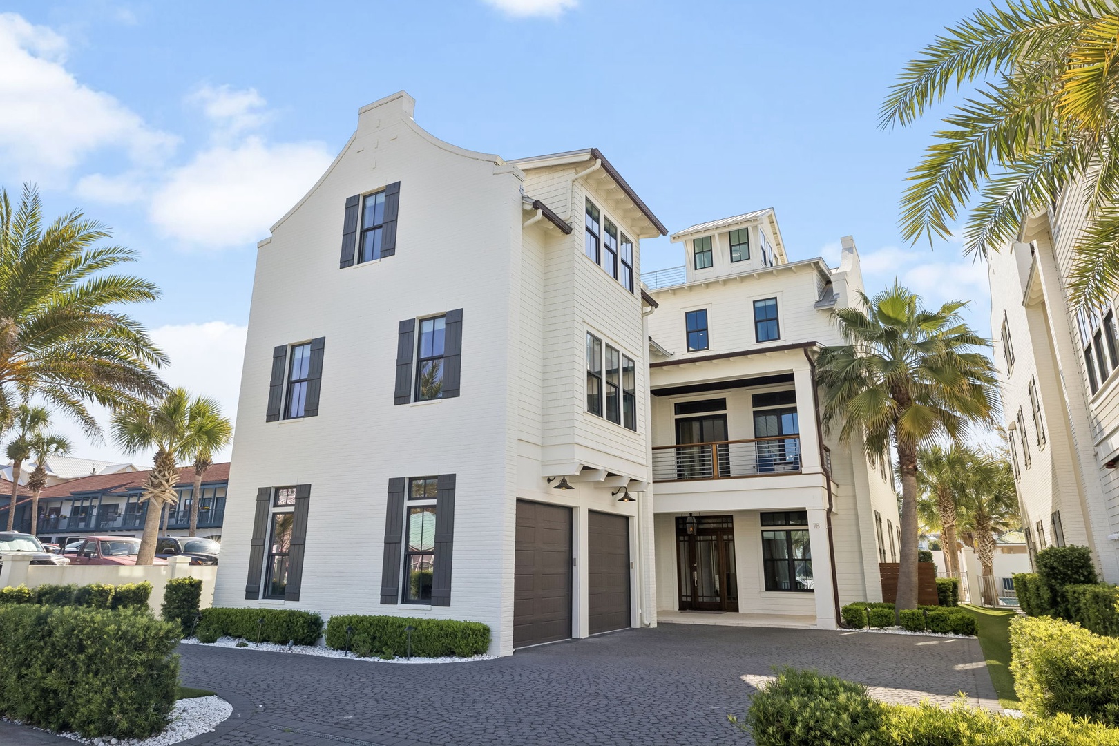Modern coastal property featuring clean white architecture surrounded by lush palm trees and manicured landscaping.