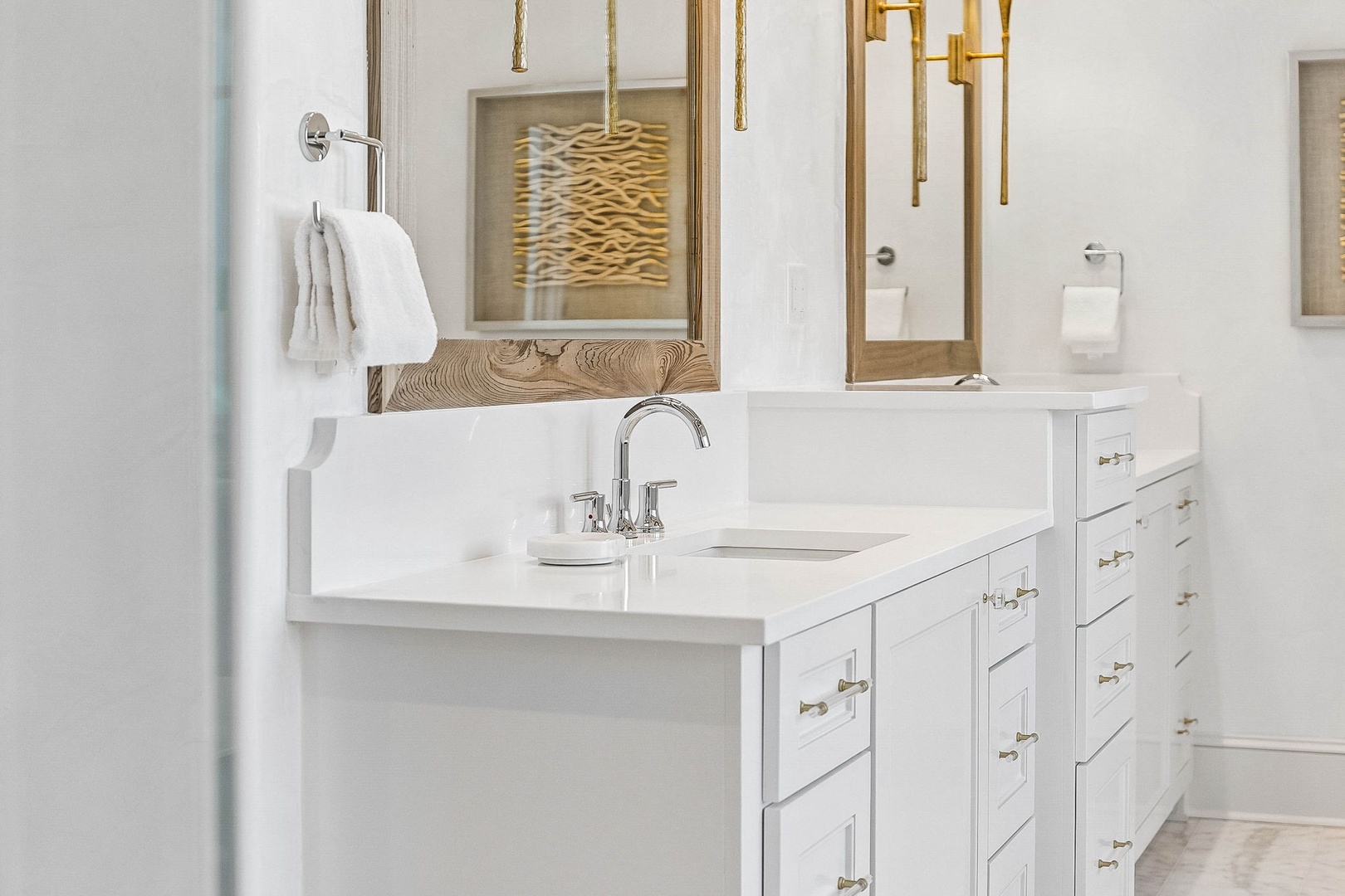 Your private bathroom features dual vanities with sleek white countertops, elegant gold fixtures, and thoughtful details like soft towels and ample storage to make your morning routine a breeze.