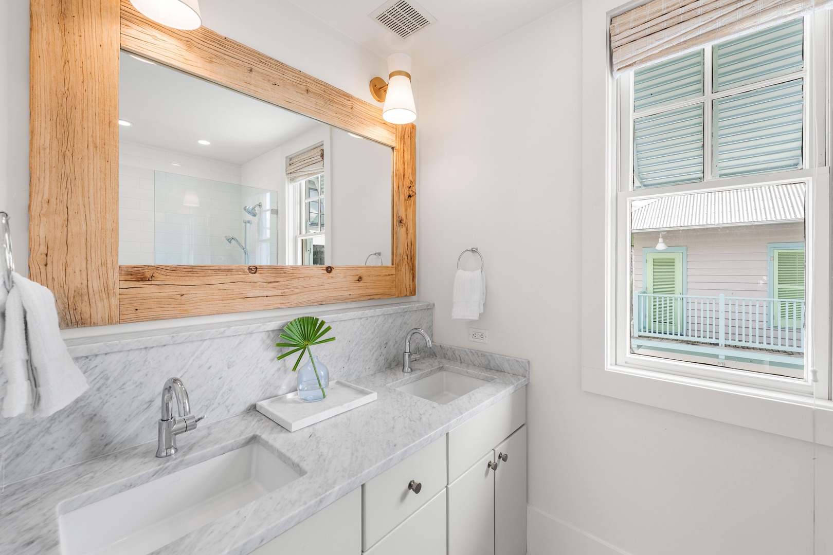 Your elegant bathroom features marble countertops, warm wood accents, and peaceful neighborhood views through the window.