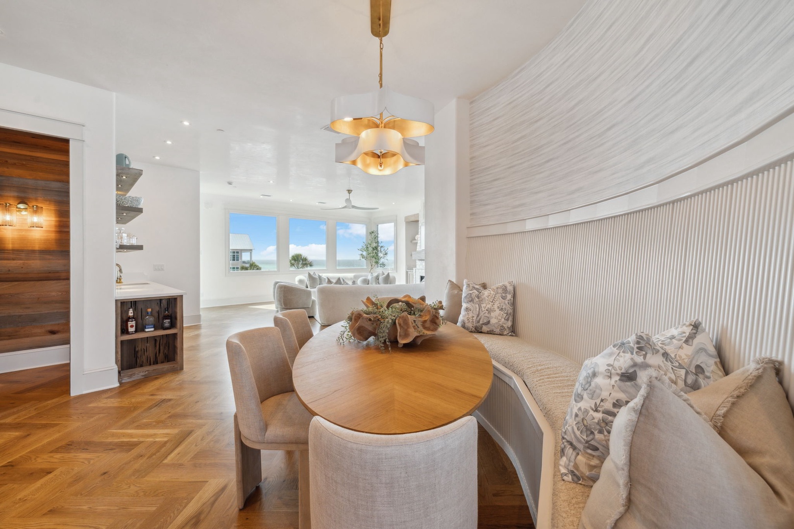 Gather for memorable meals in this elegant dining area, where a golden chandelier sets the mood and soft coastal light streams through the windows to complete your beachside retreat.
