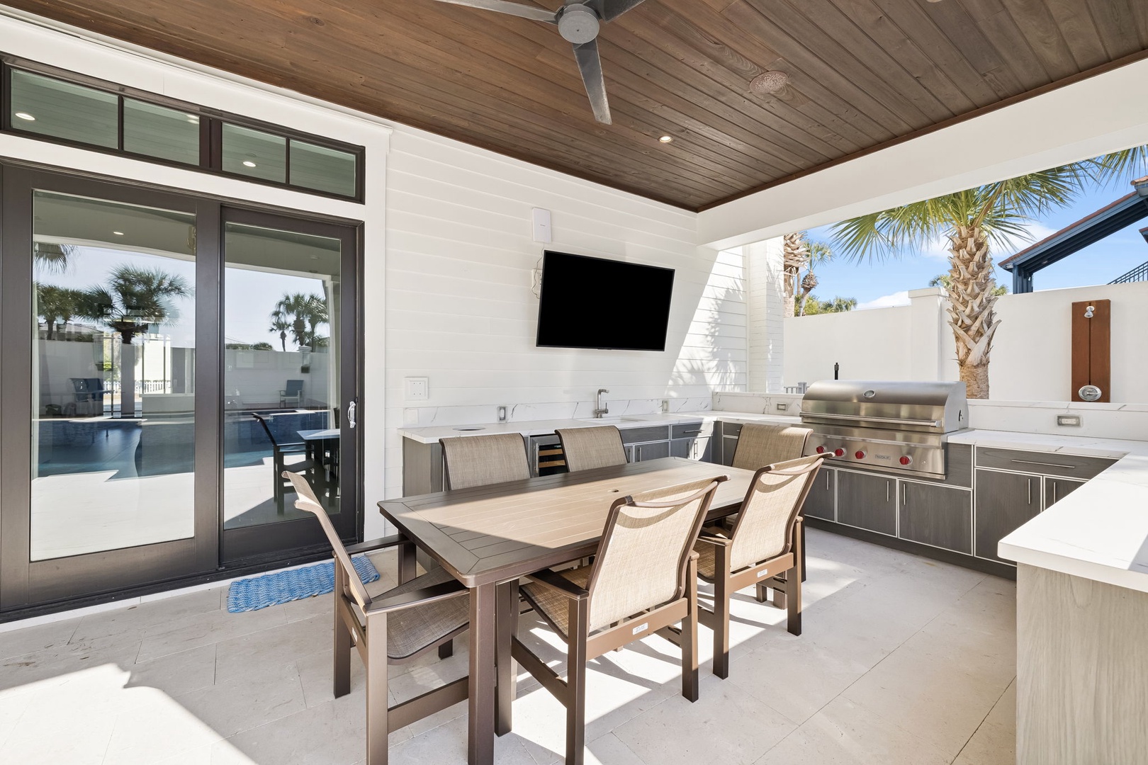 Step into your covered outdoor kitchen with stainless steel appliances, where you'll create memorable meals while enjoying pool views.