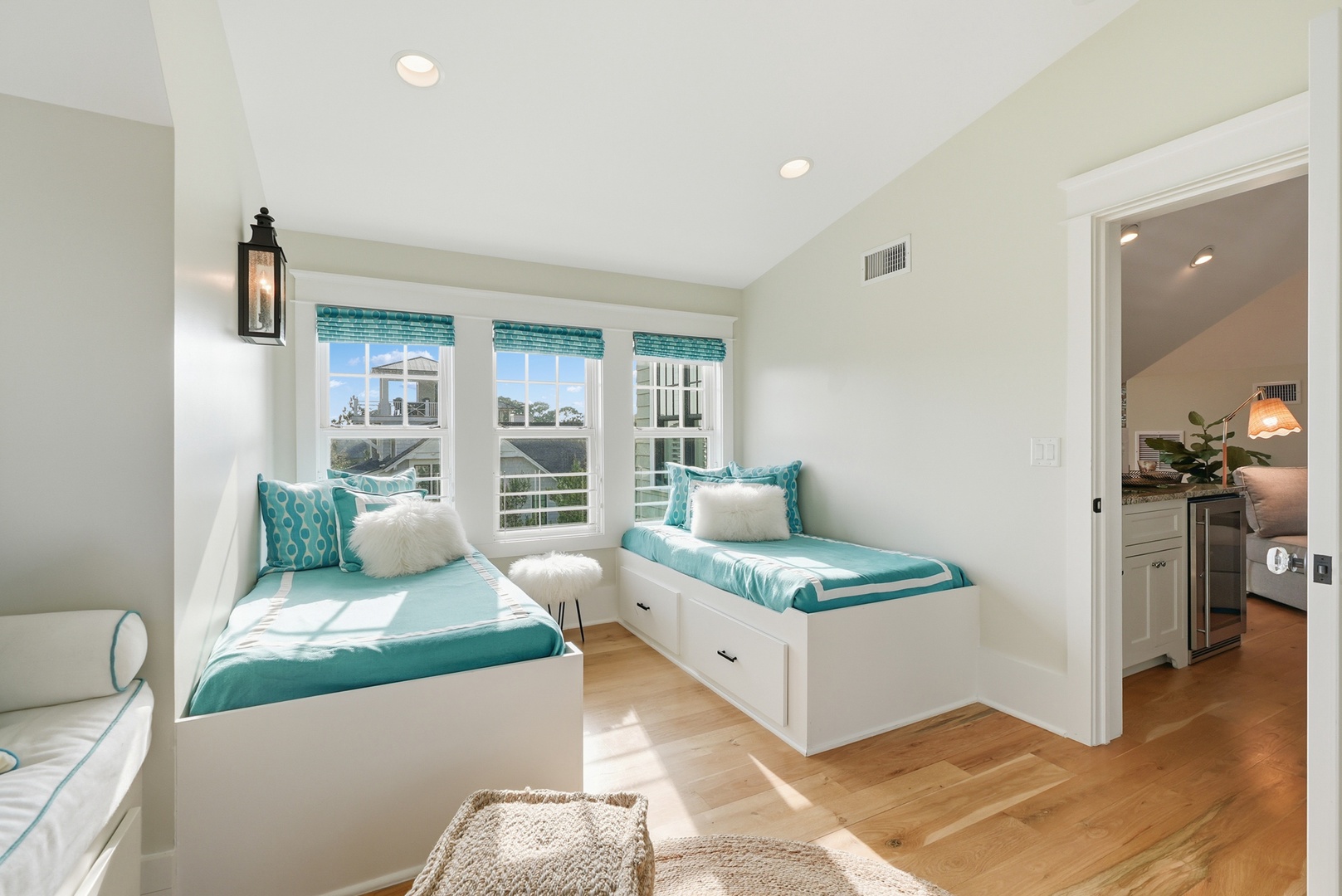Unwind in your bright coastal retreat with twin built-in beds dressed in aqua accents, perfect for sharing stories as sunlight streams through windows overlooking the neighborhood.