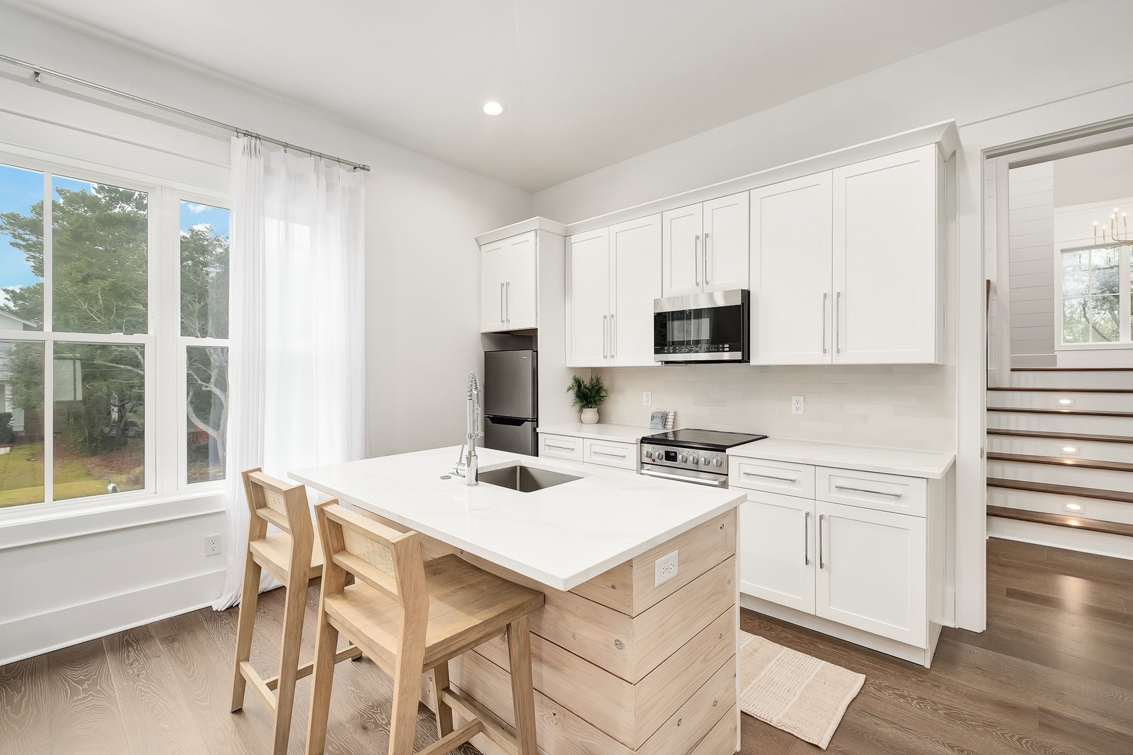Your bright kitchen features sleek white cabinetry, modern appliances, and a cozy island perfect for morning coffee or preparing meals together.