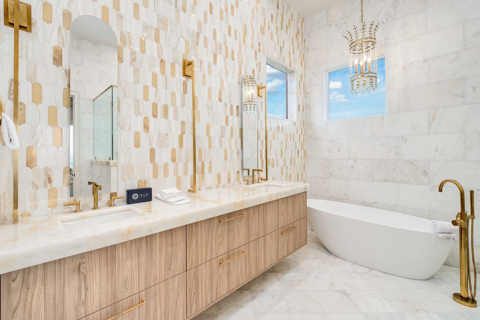 Step into your spa-like sanctuary with elegant marble, designer fixtures in gold, and a freestanding soaking tub perfect for unwinding after your adventures.