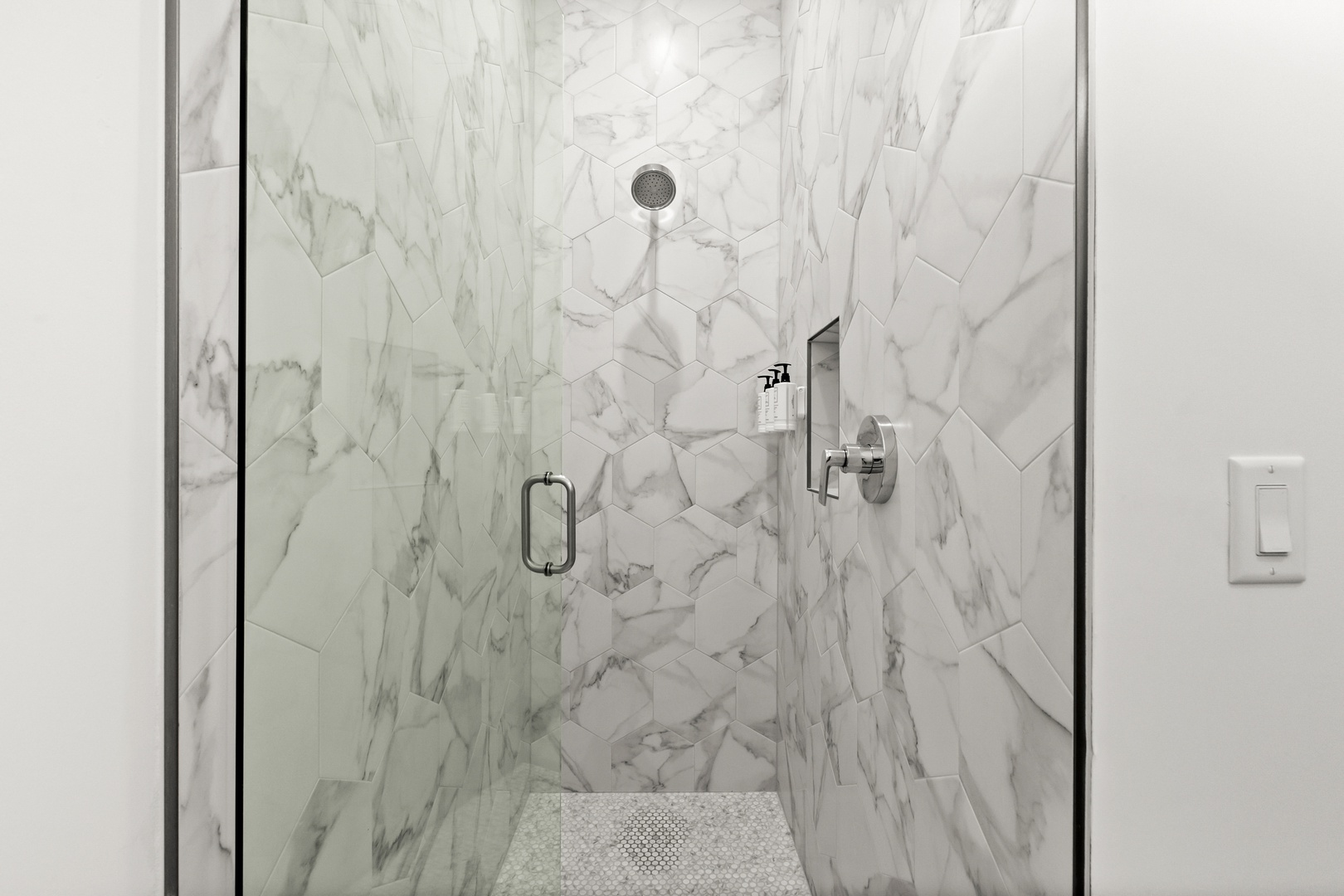 Your private oasis awaits in this stunning marble-tiled walk-in shower, complete with a rainfall showerhead and modern fixtures for a truly refreshing escape.