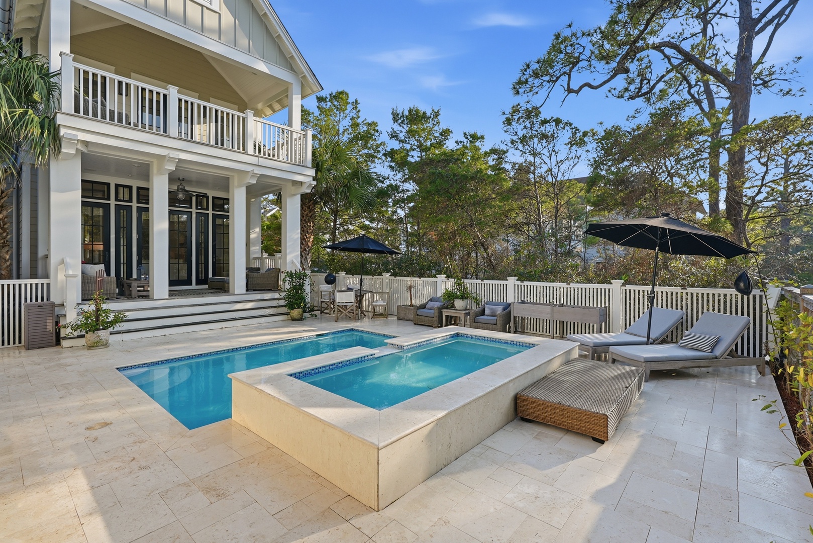 A serene coastal retreat featuring a private saltwater pool and adjacent spa, surrounded by mature pines. The elegant two-story home offers classic southern architecture with wraparound porches.